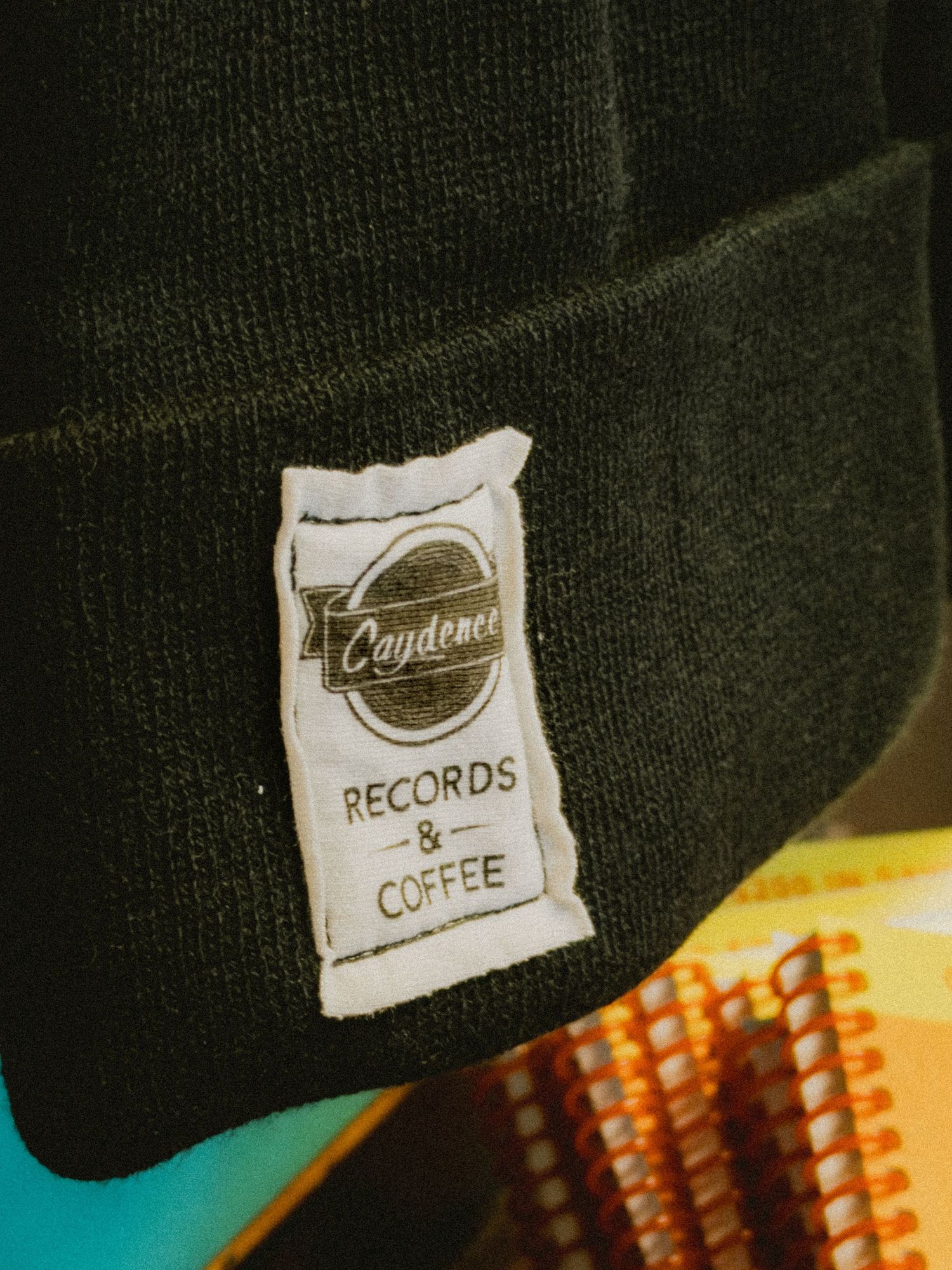 Close-up view of a black fabric garment with a white clothing tag showing the Converse brand logo and text.