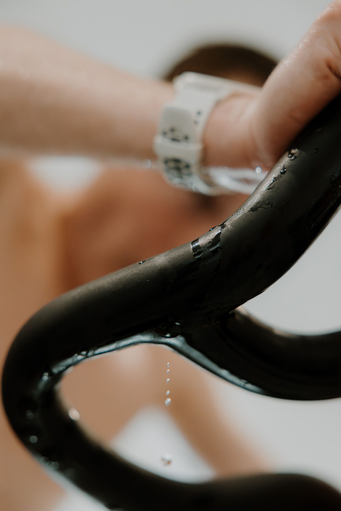 Water droplets falling from a curved black surface in macro photography.