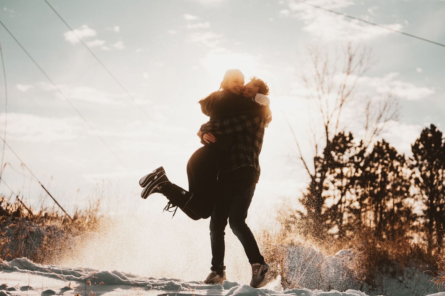 A silhouetted figure snowboards down a snowy slope against a bright winter sky.