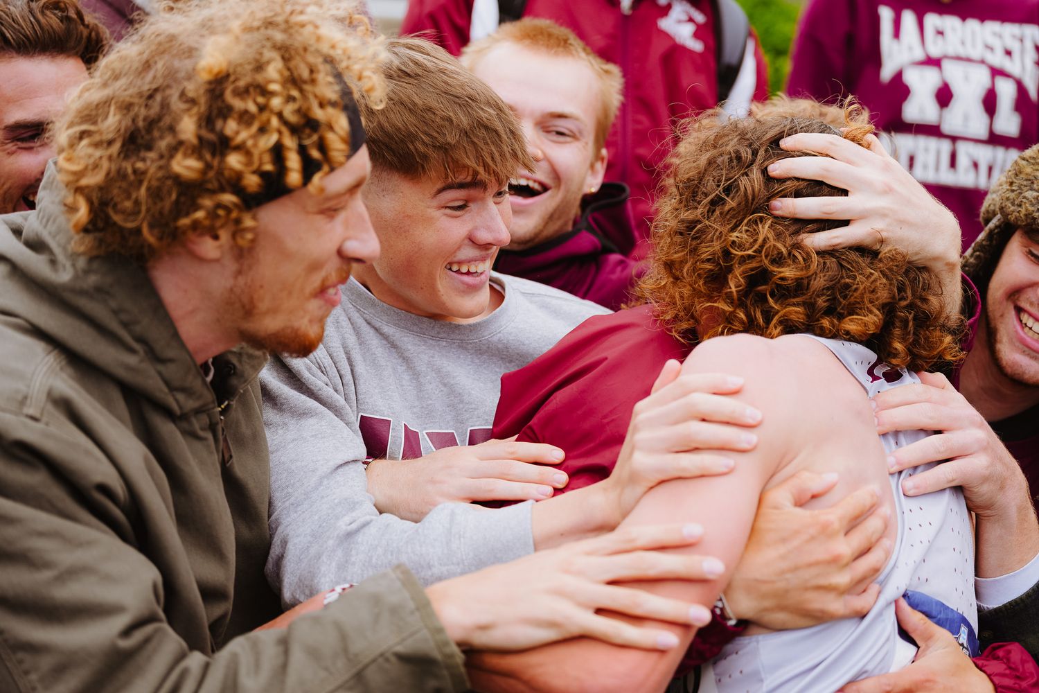 Fans in maroon jerseys excitedly reach out for autographs at a sporting event.