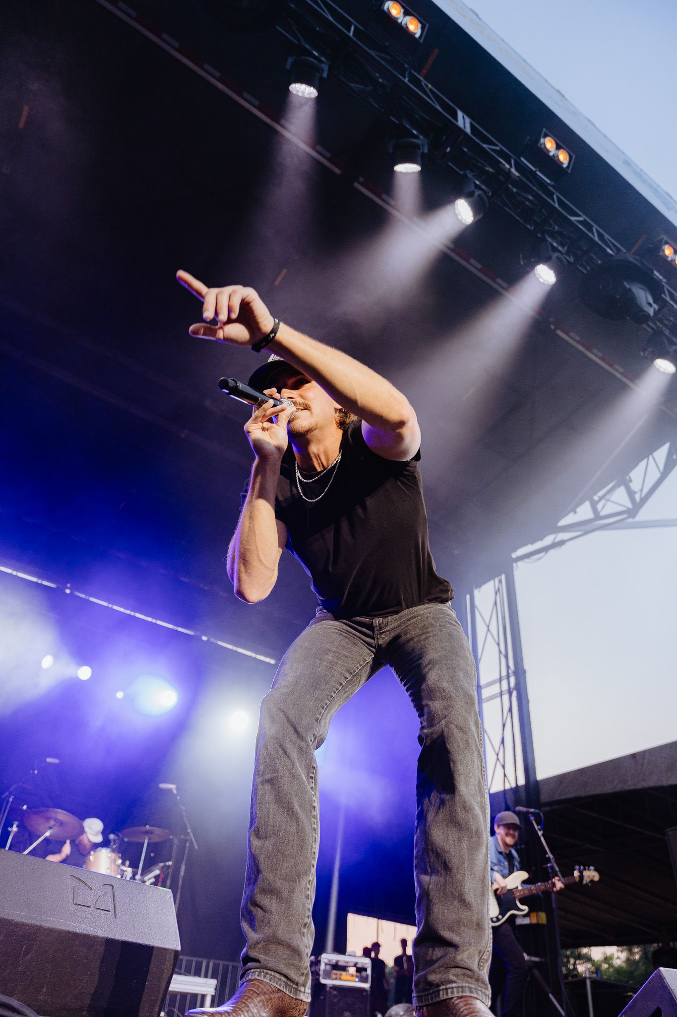 Energetic performer in black shirt and jeans dancing on stage with dramatic purple lighting effects.