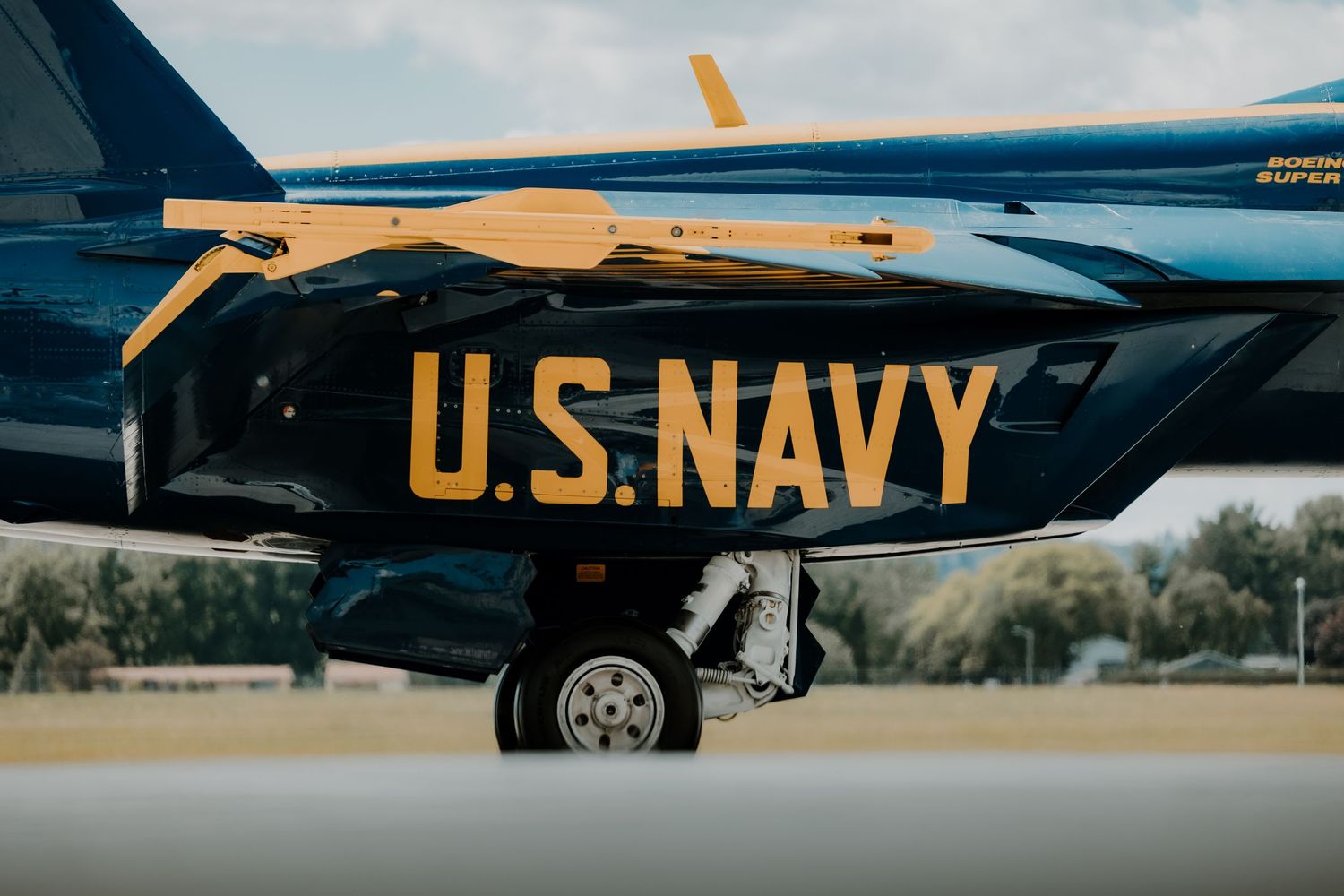 Close-up view of U.S. Navy lettering in gold on the side of a dark blue military aircraft.
