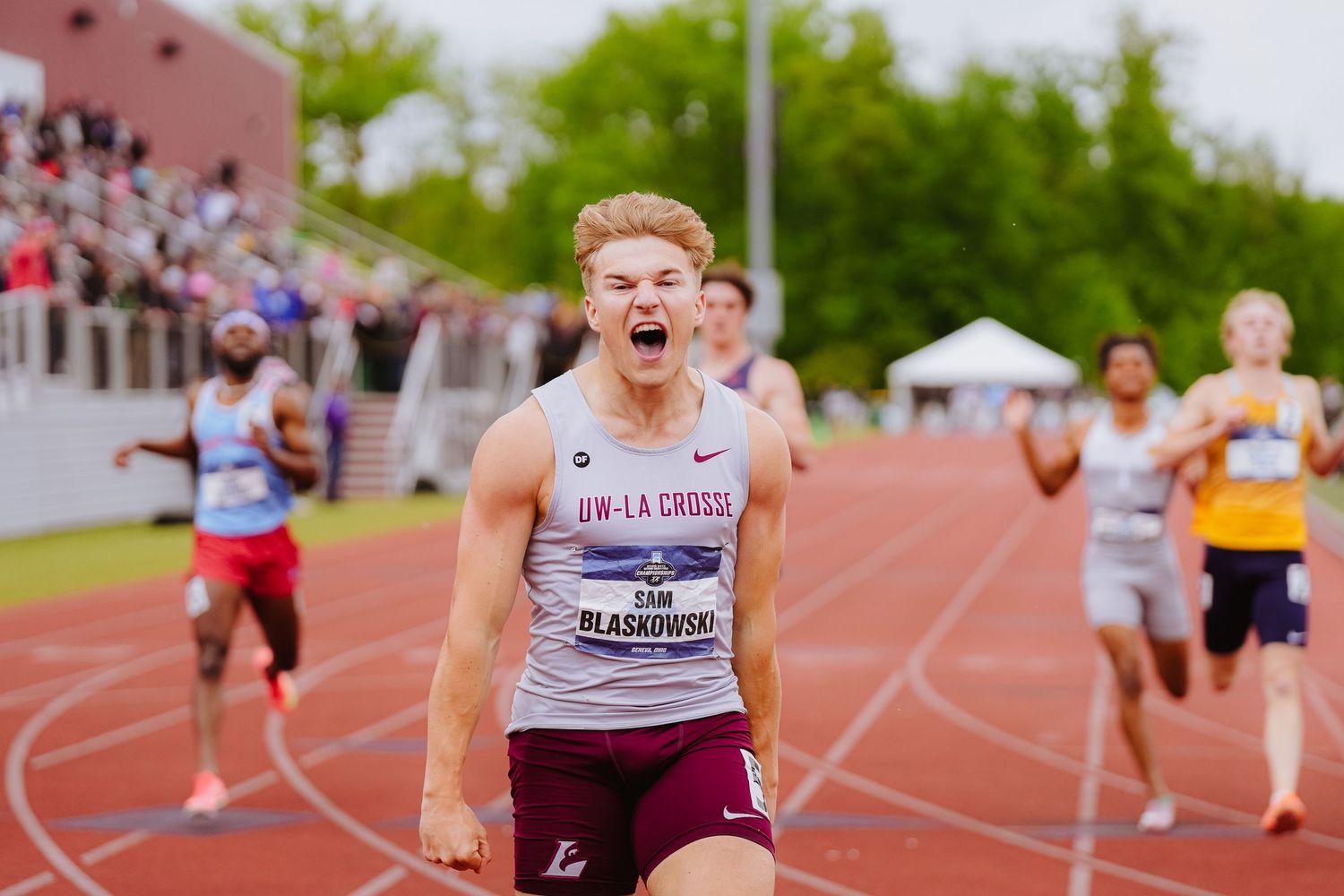 Runner shows intense emotion while competing on outdoor track during athletic competition.