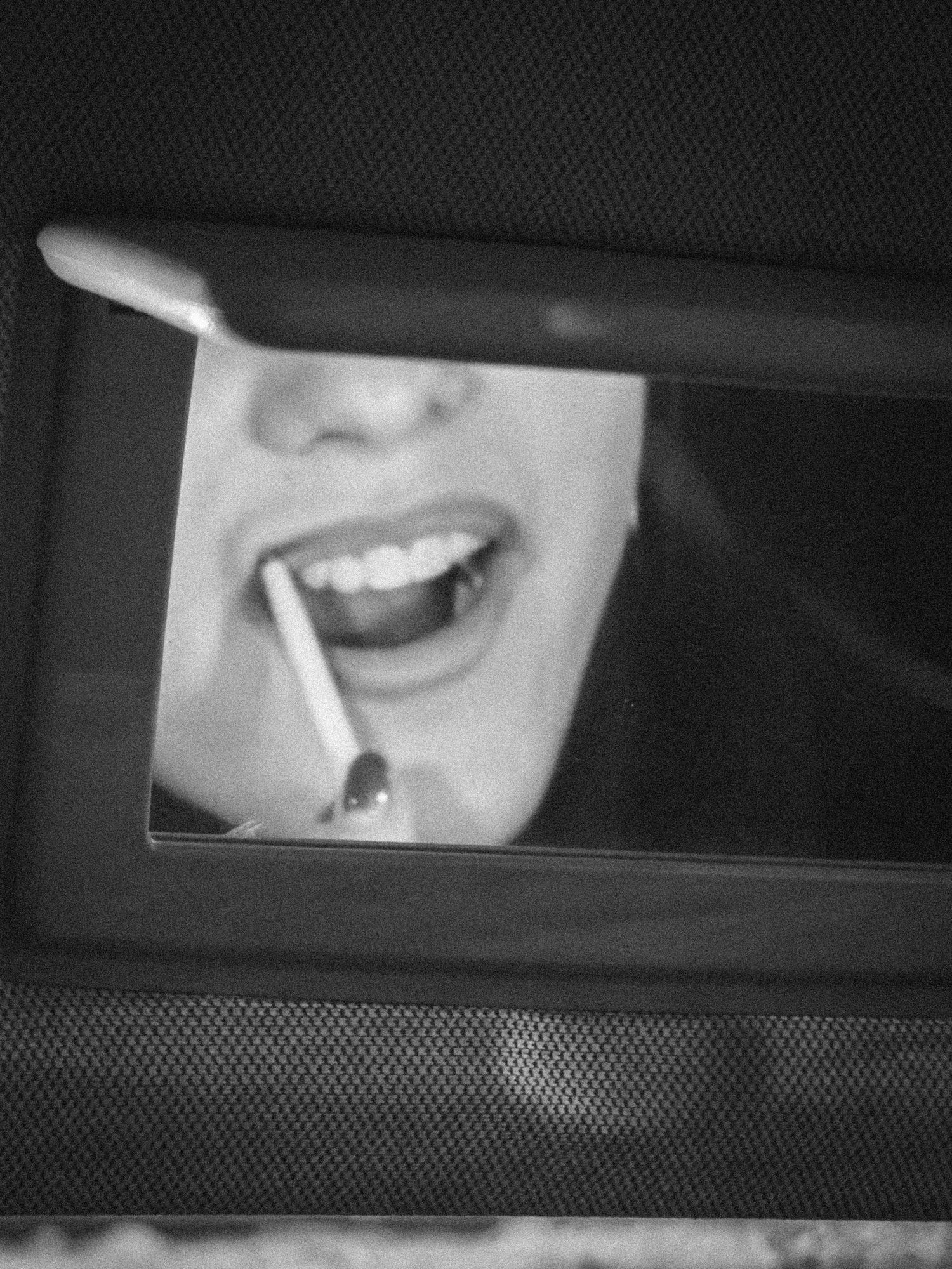 Black and white artistic photograph showing a series of smiling expressions through a car window reflection.