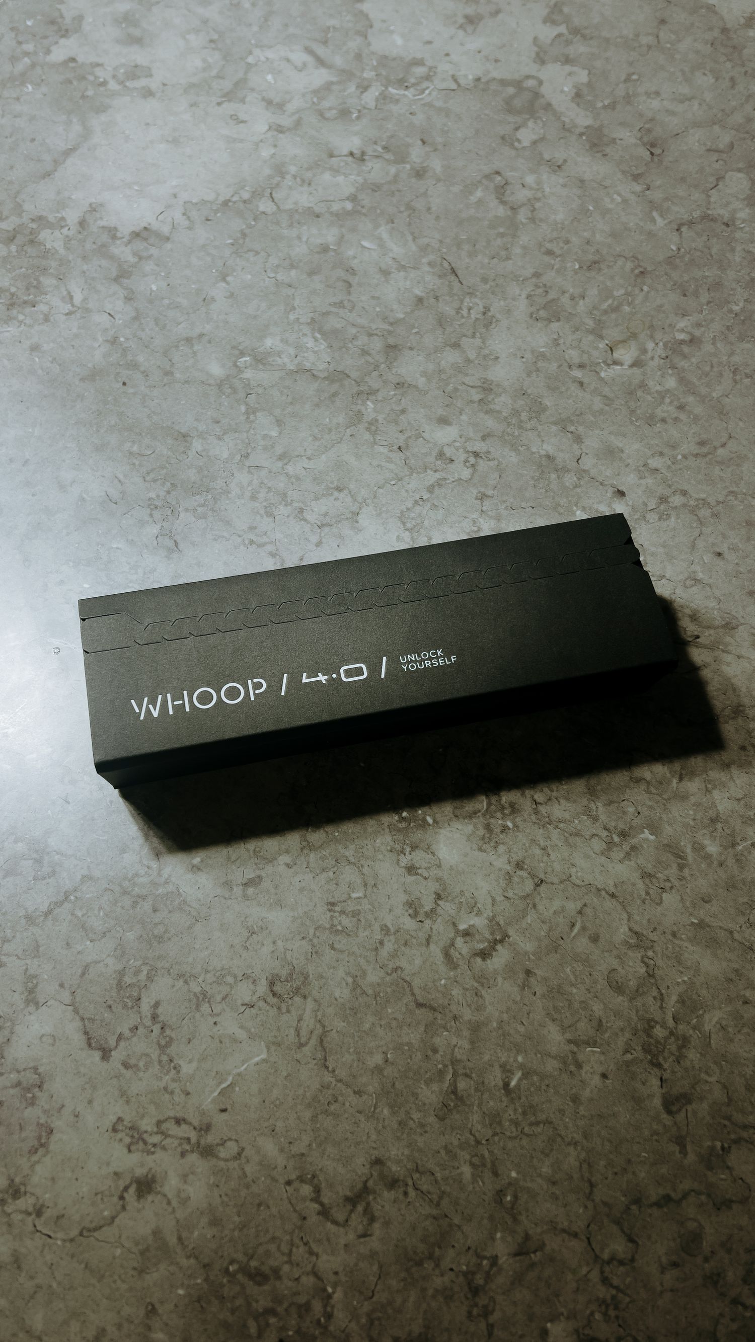 A black Whoop box sitting on a textured gray concrete or stone surface.