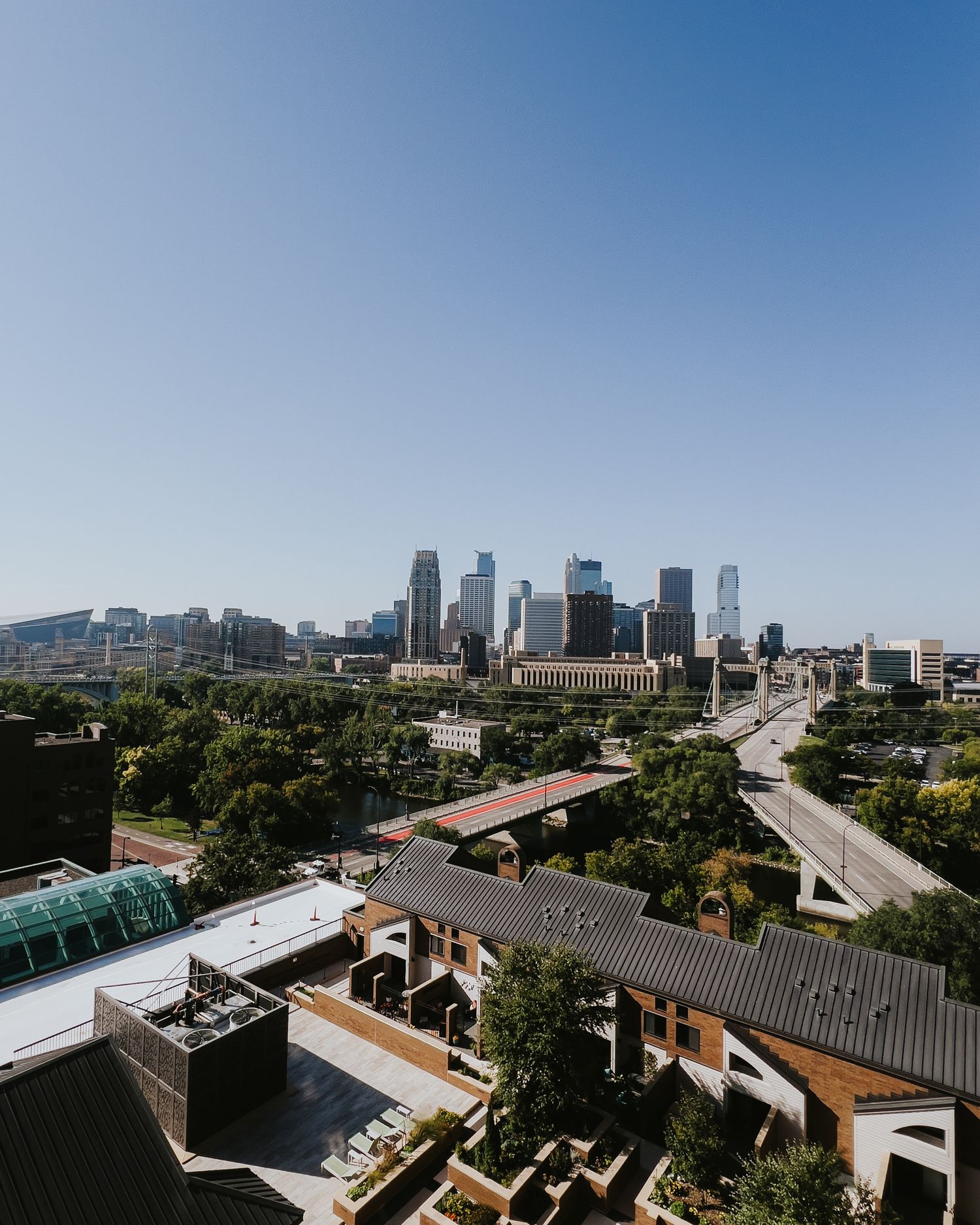 Panoramic cityscape view of Minneapolis skyline on a sunny day showing modern buildings and surrounding neighborhoods.