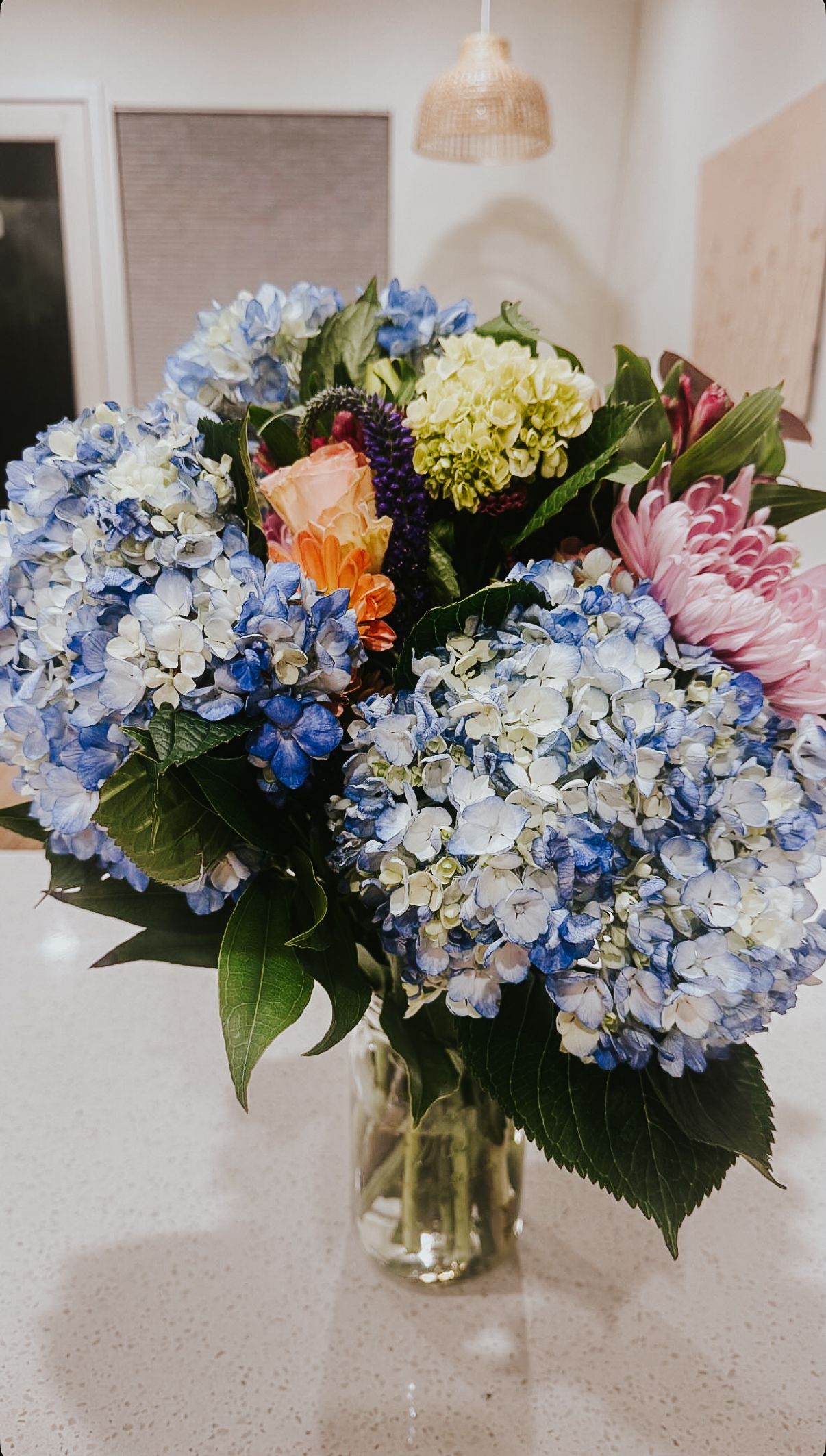 Beautiful floral arrangements featuring blue and white hydrangeas with mixed blooms in glass vases displayed in a row.
