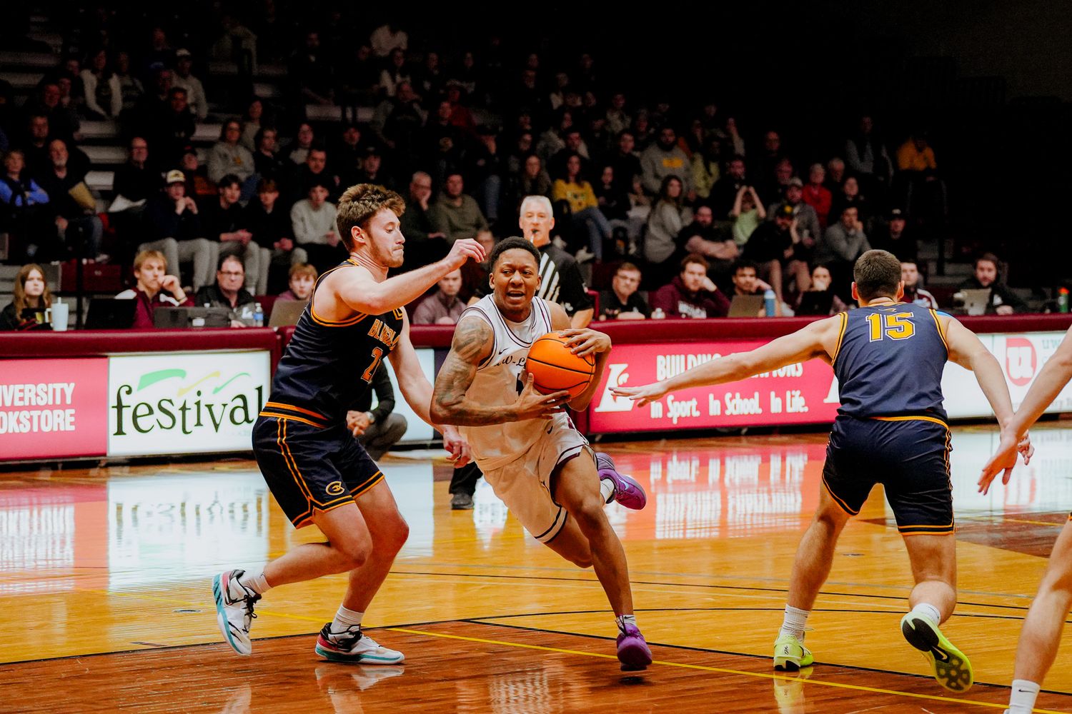 Basketball players compete for possession of the ball during an intense game on a hardwood court.