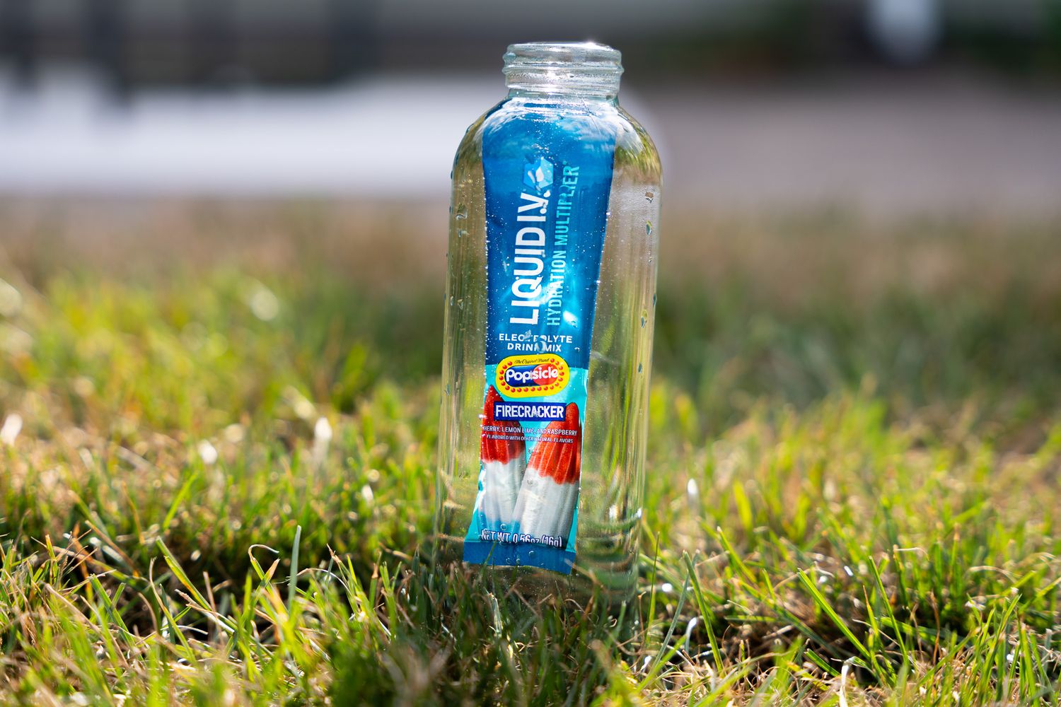 A can of Bud Light beer resting in green grass with sunlight illuminating the background.