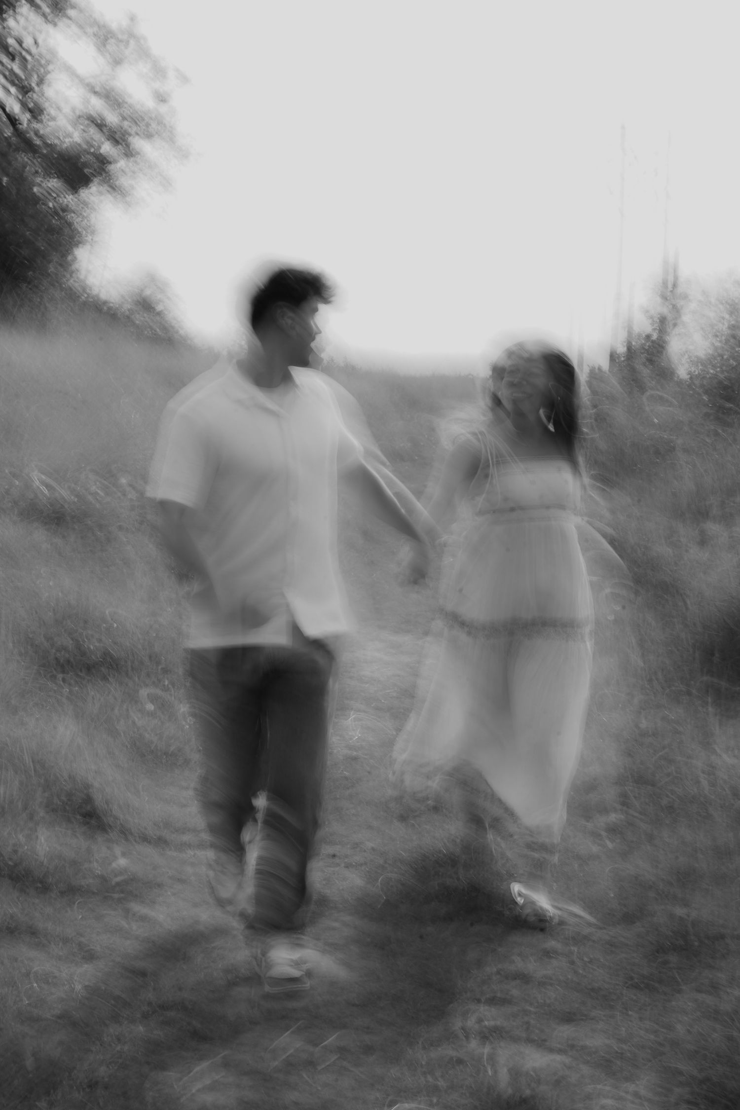 A series of blurry black and white photographs showing ghostly figures moving through a wooded area in an artistic sequence.