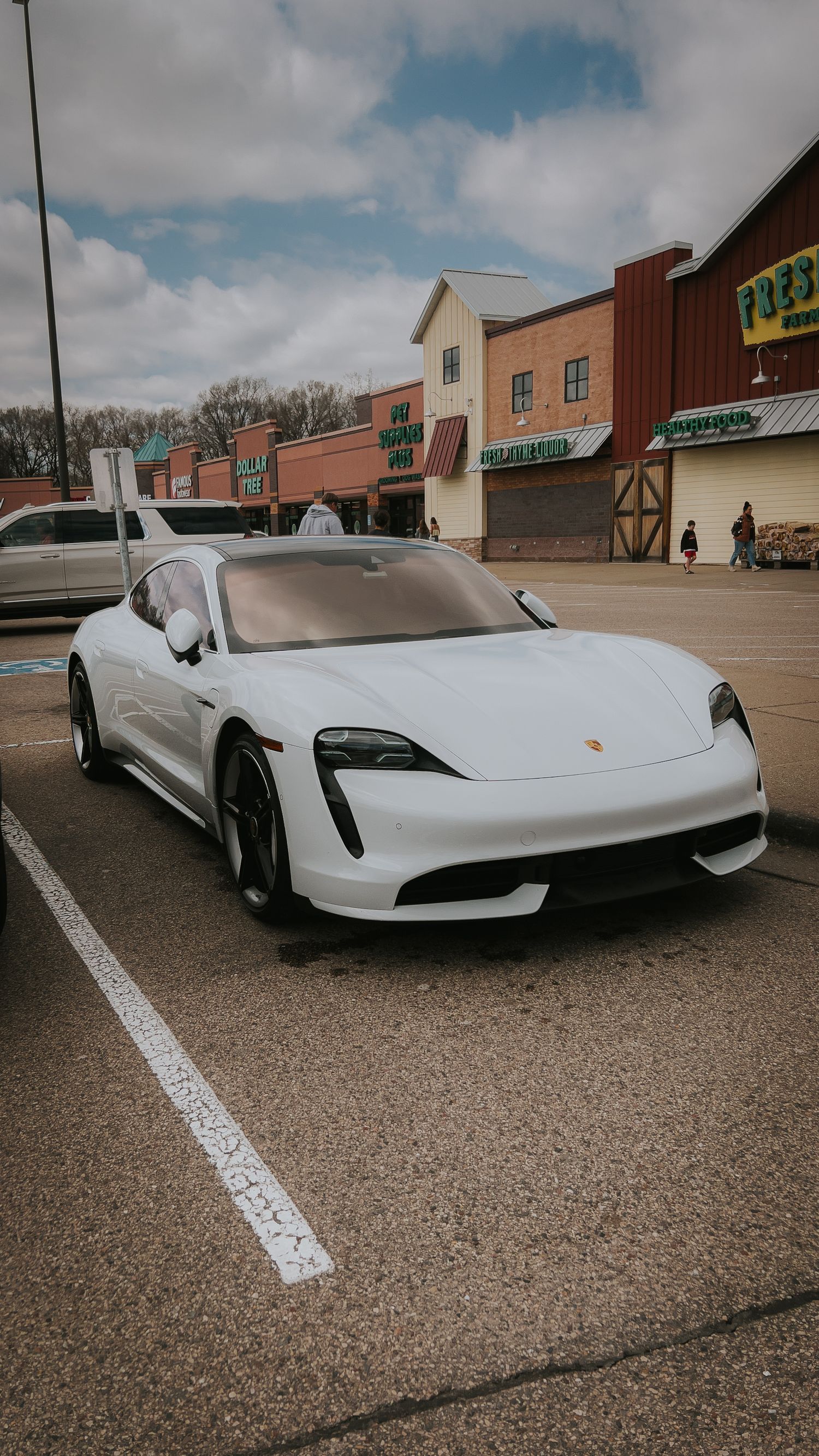 A white Porsche Taycan sports car parked in a shopping center lot shown from multiple angles.