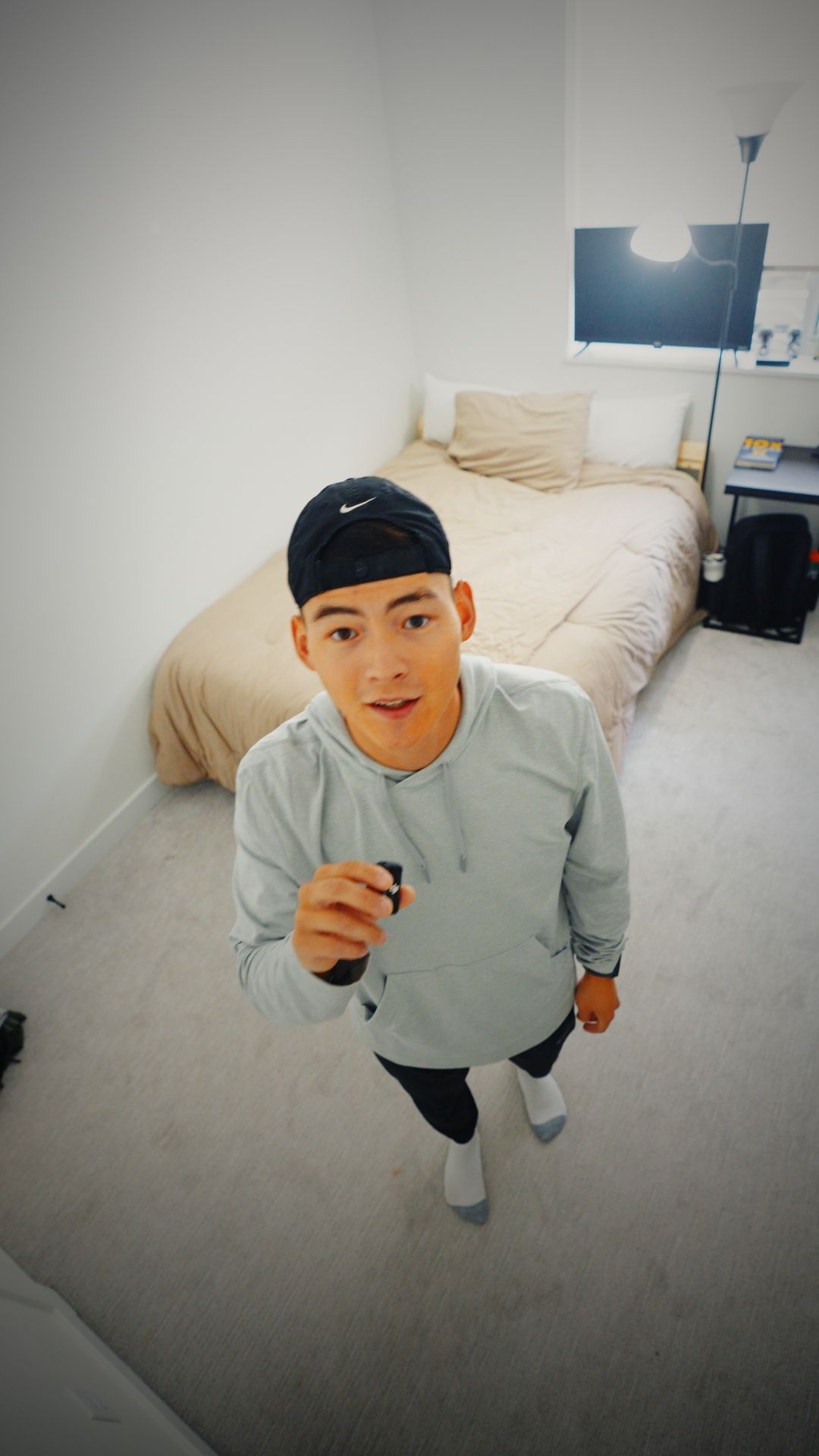 A sequence of four fisheye lens photos showing someone in a gray sweatshirt and black cap making playful poses indoors.