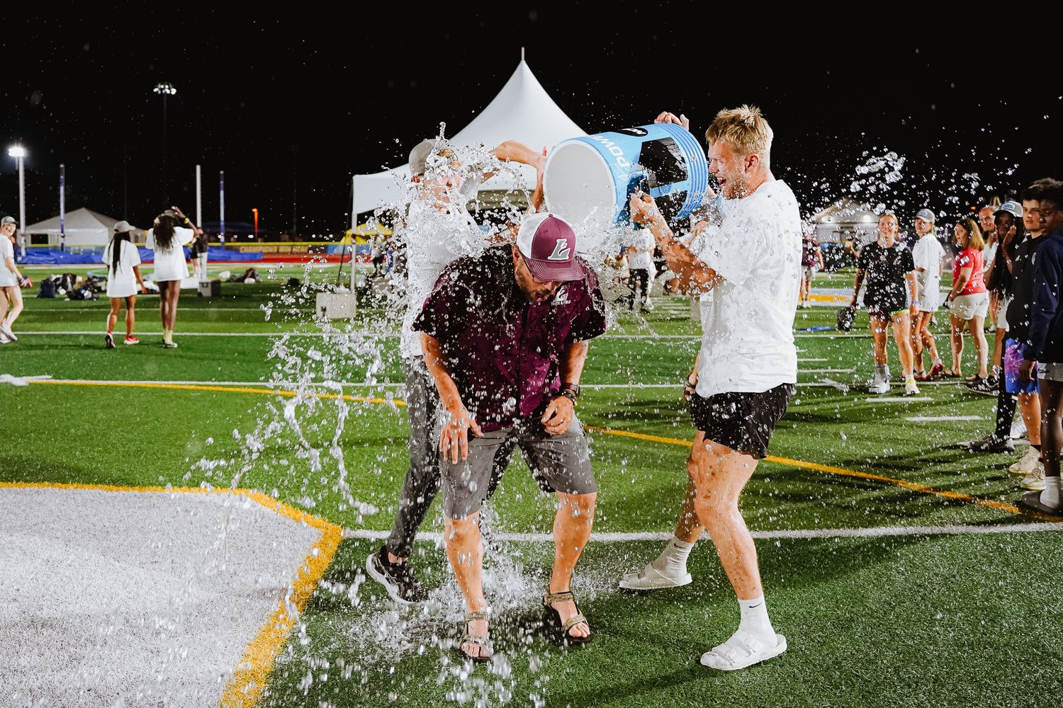 People playing in water sprinklers on a sunny day at an outdoor recreational event.