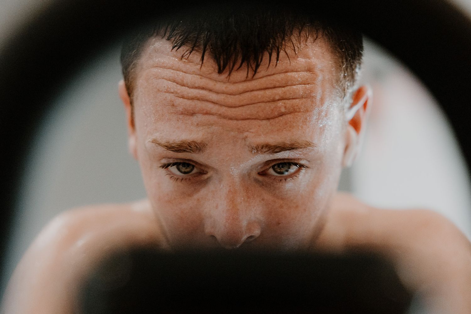 Close-up view of dark hair and forehead showing sweat or moisture.