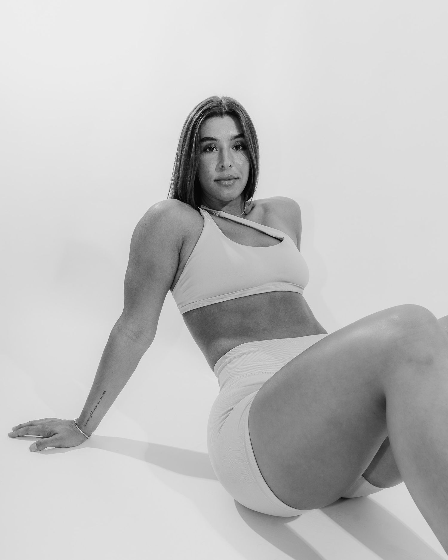 A series of minimalist black and white photos showing a figure in white undergarments against a light background.