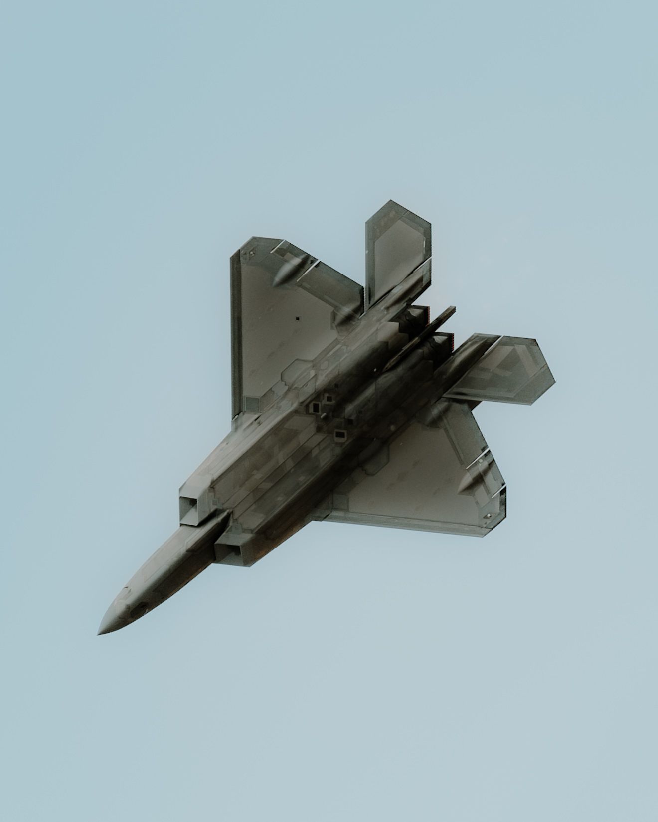 A sequence of four images showing a fighter jet performing a roll maneuver against a light blue sky background.