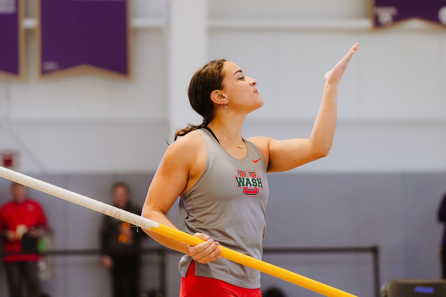 Gymnast performing a routine on uneven bars with graceful form and extension during competition.