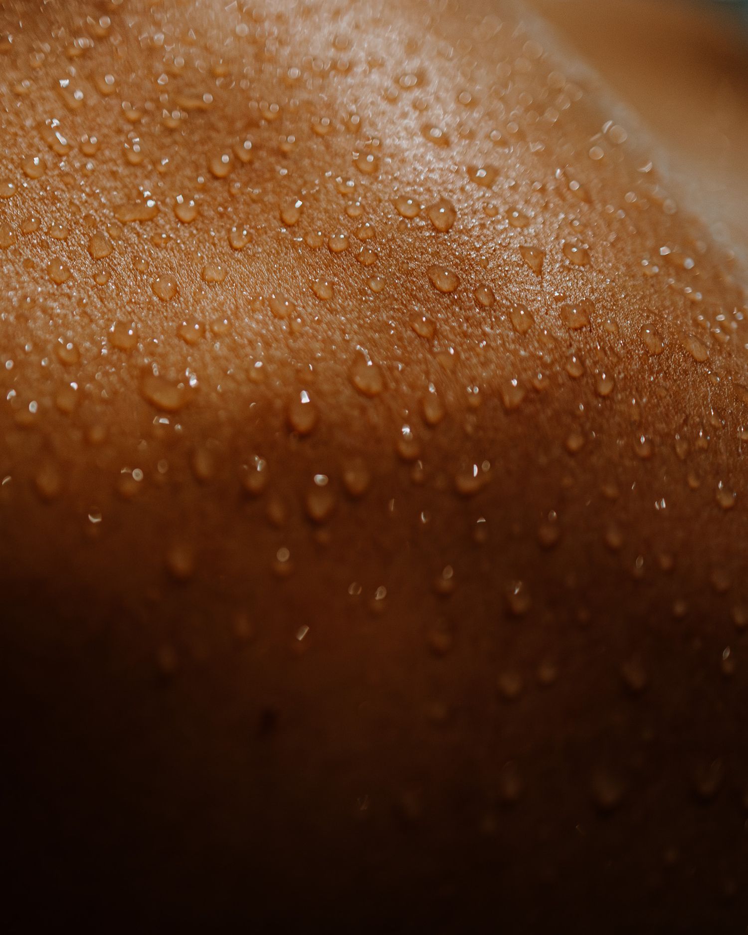 Macro photography of water droplets on skin creating a shimmering textured surface.