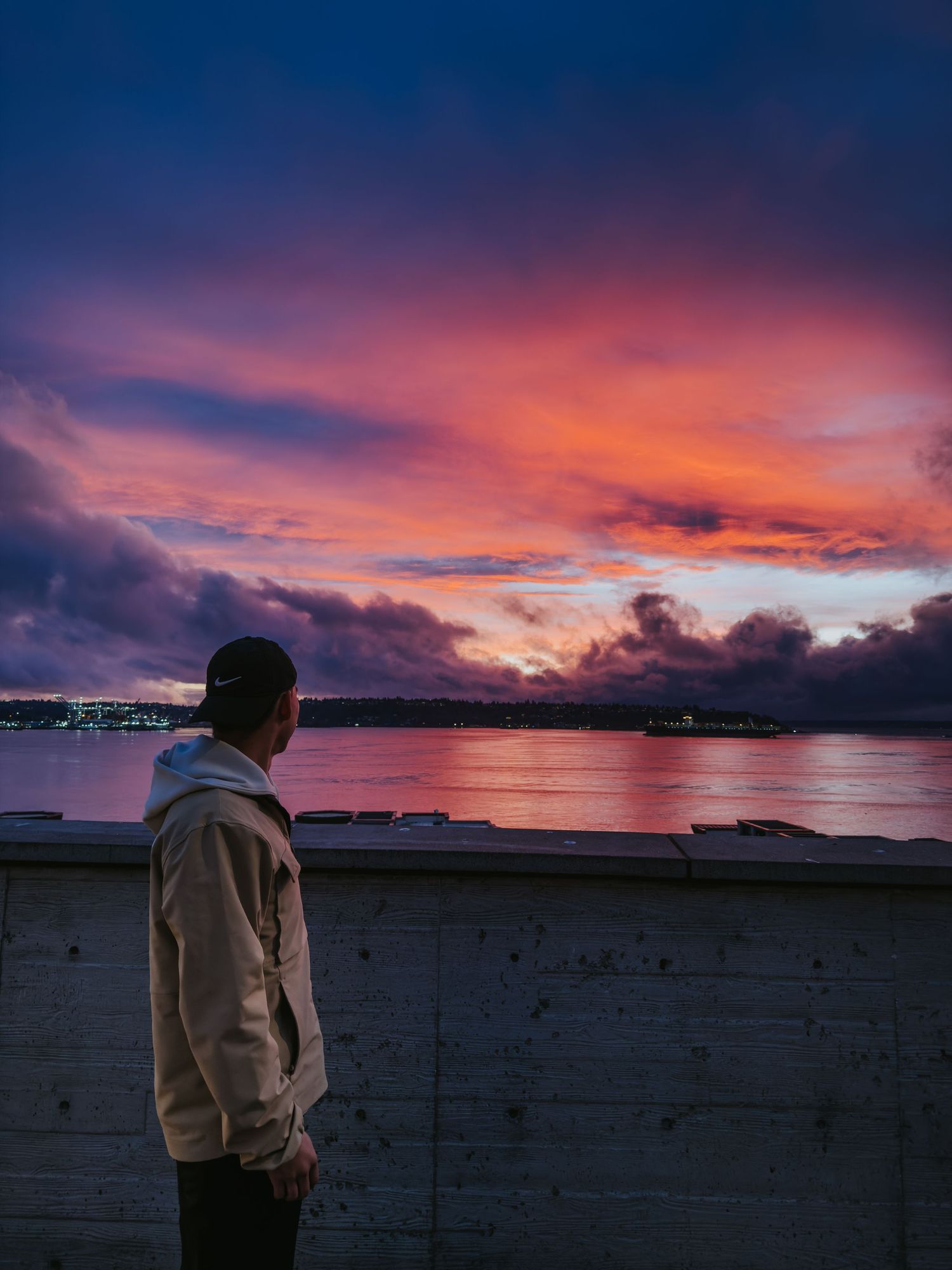 Dramatic purple and orange sunset sky over a dark silhouetted landscape with clouds reflecting vibrant colors.