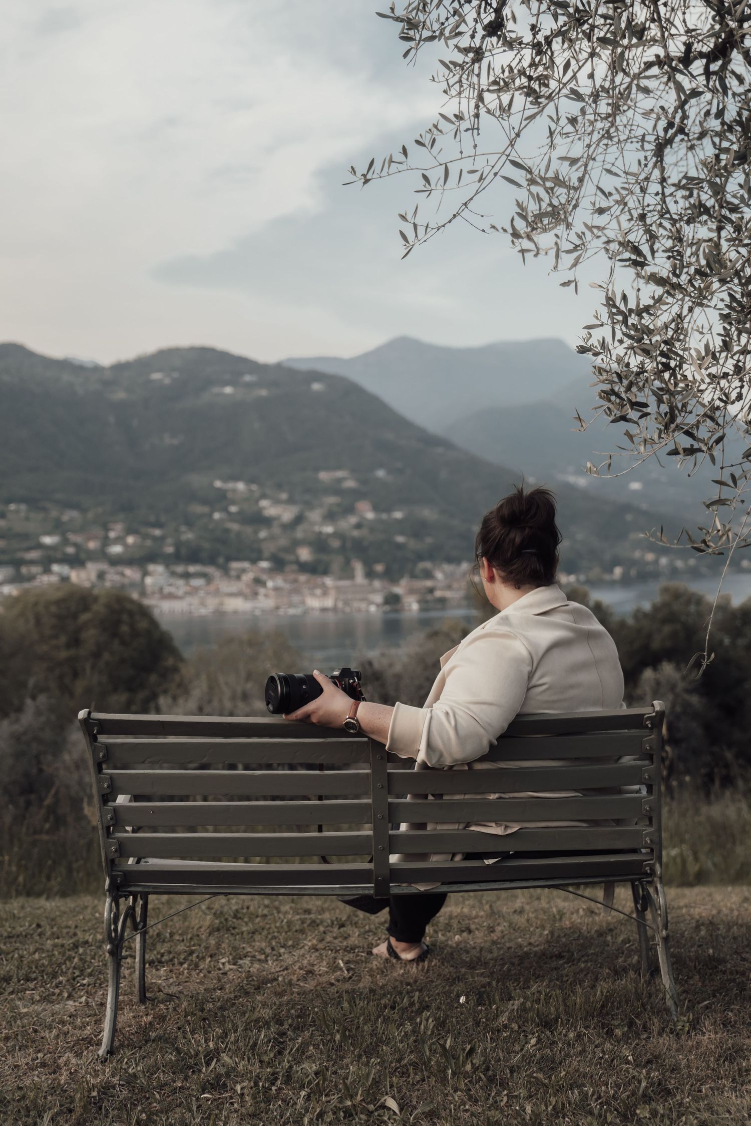Eileen Camin auf einer Bank am Gardasee mit Blick auf See und Berge