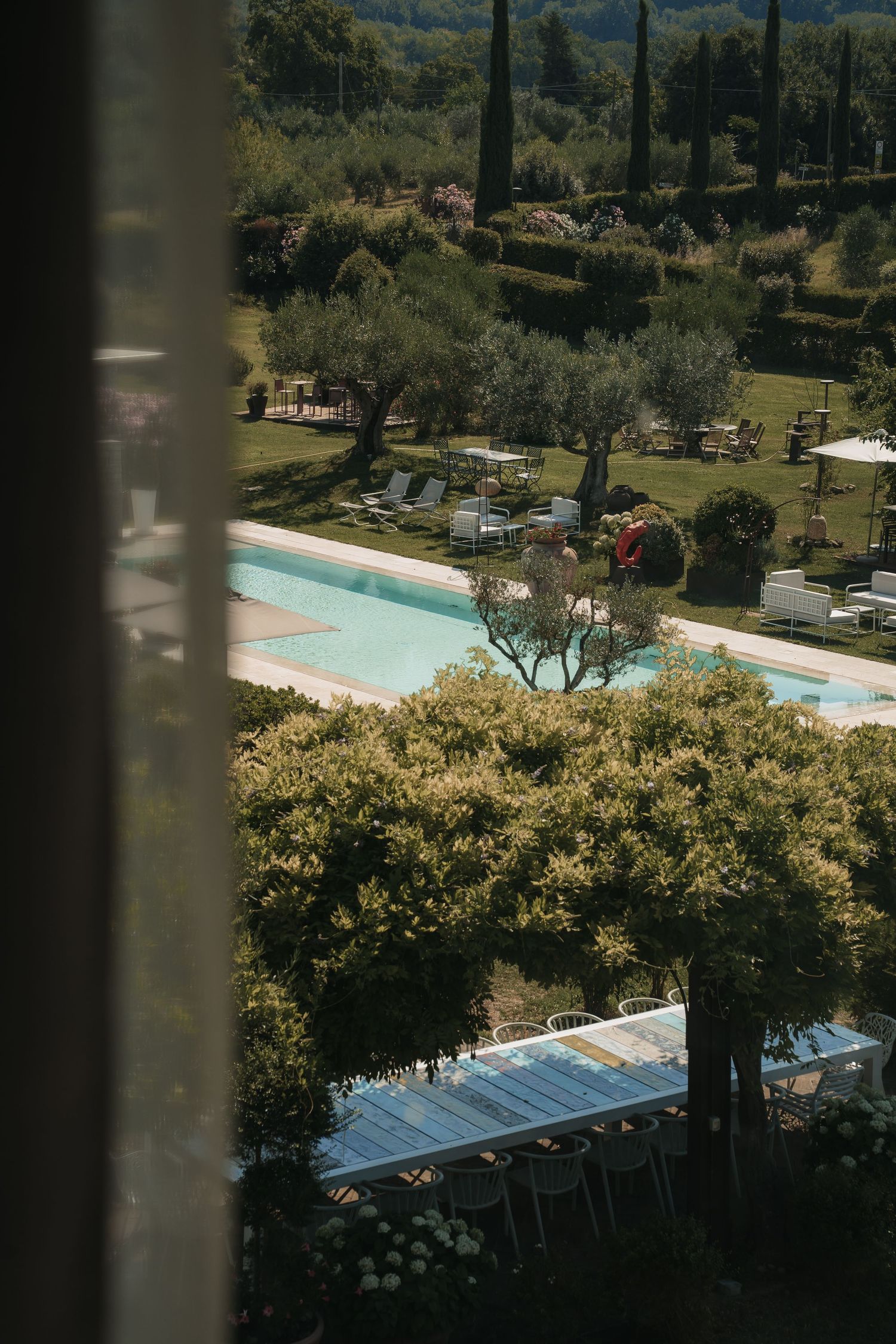 Blick durch Zypressen auf den Pool der Hochzeitsvilla