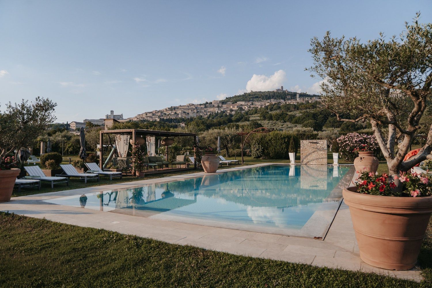 Pool mit Liegen und Blick auf ein italienisches Bergdorf