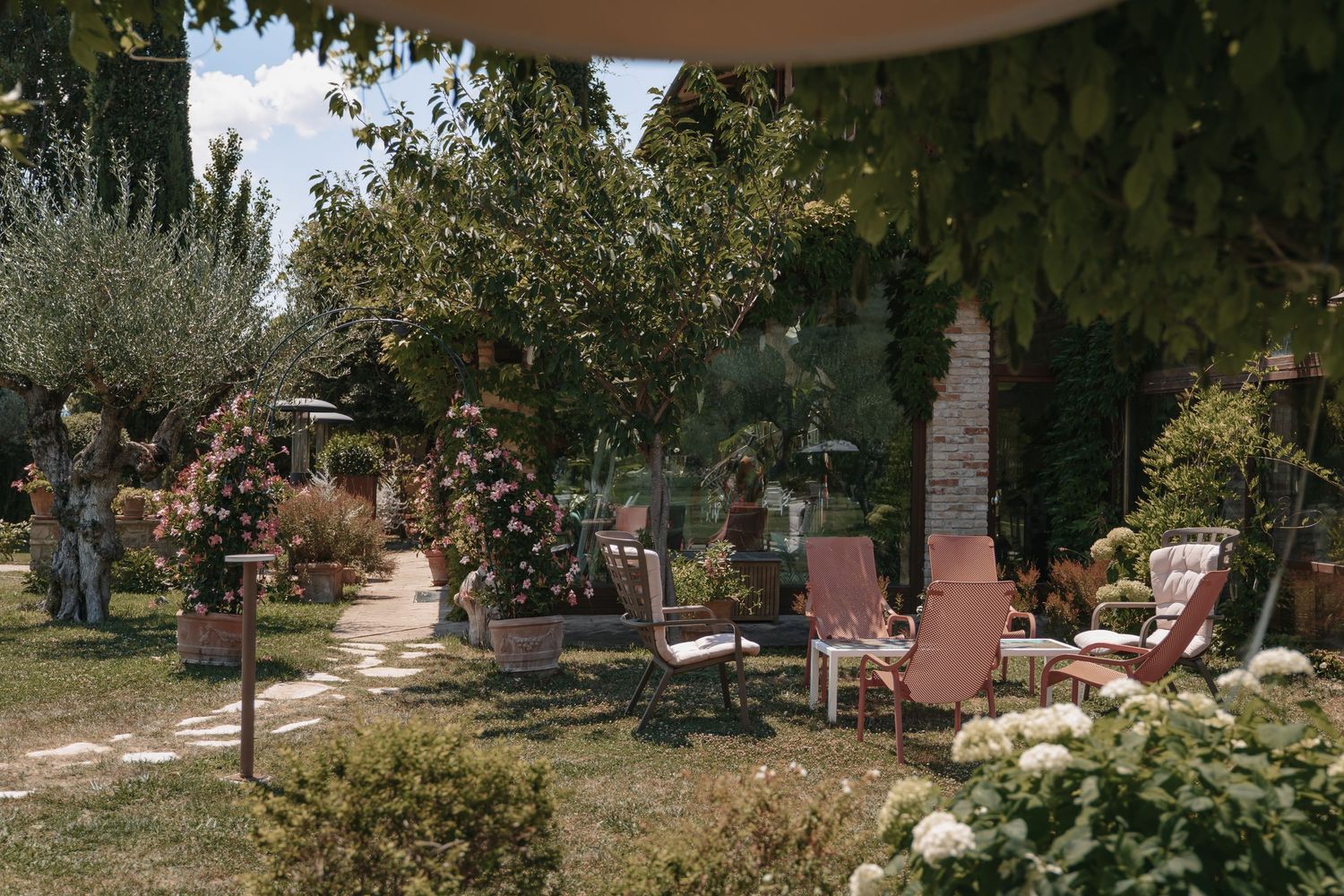 Mediterraner Garten mit Sitzplätzen und Sonnenschirmen