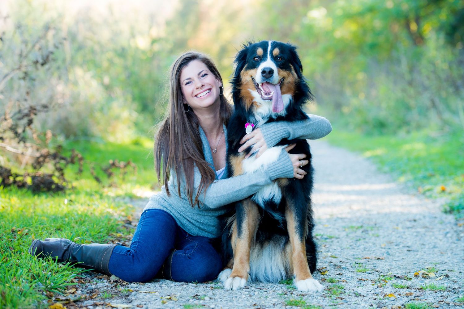 Bernese Mountain Dog with happy expression poses on nature trail with companion.
