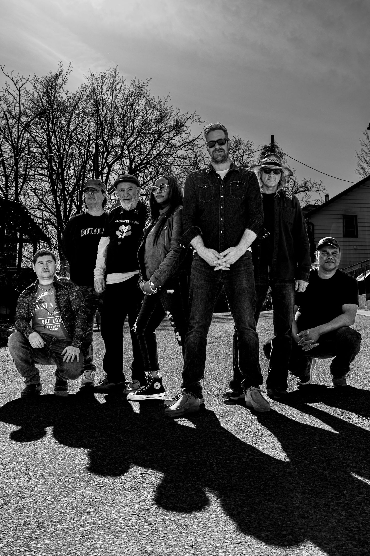 Black and white portrait of band members arranged in casual poses outdoors.