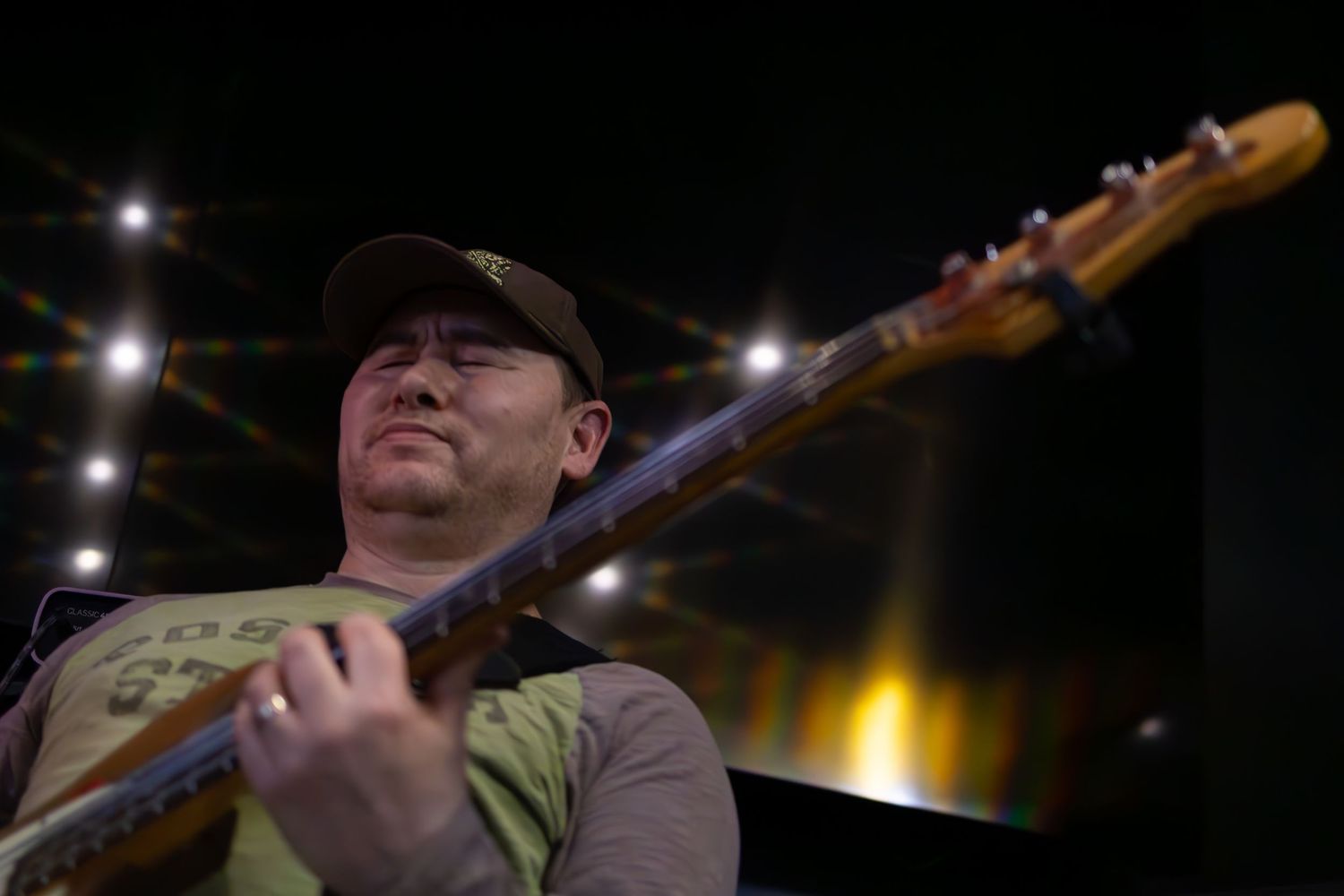 Musician performs on stage with a bass guitar under dramatic lighting at a nighttime concert performance.
