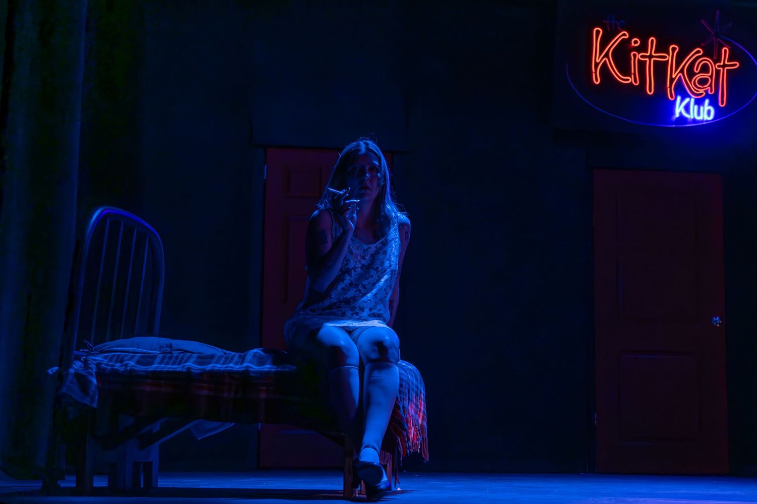 A dark concert stage with blue lighting and silhouetted figures performing music in a dramatic atmosphere.