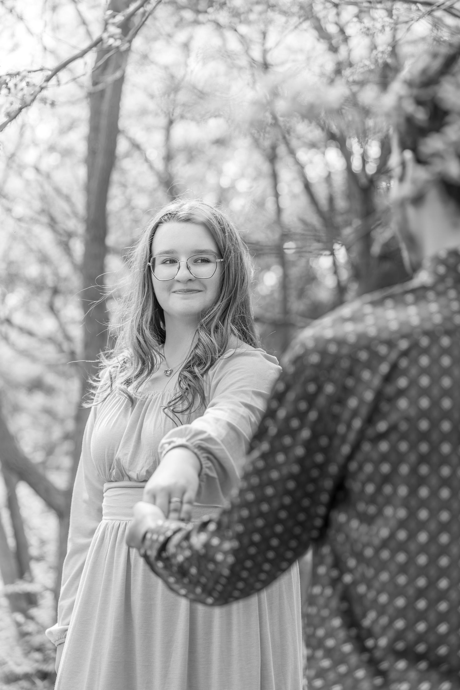 Black and white portrait series showing a person in a light colored dress posing against a natural outdoor background.