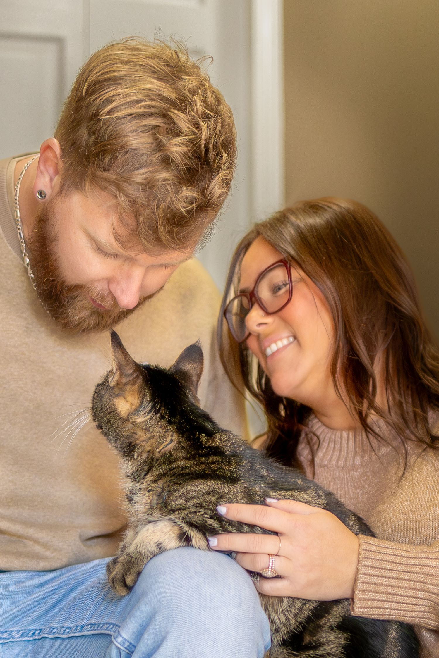 A person in a beige sweater shares a tender moment with their gray cat in a series of connected photos.