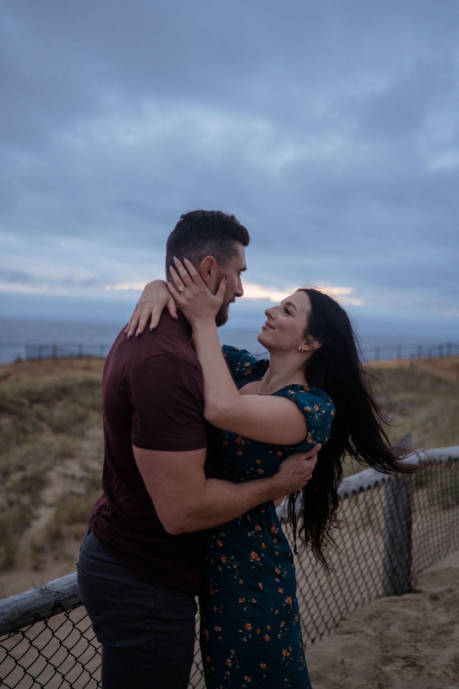 A romantic sunset embrace against a moody coastal backdrop.