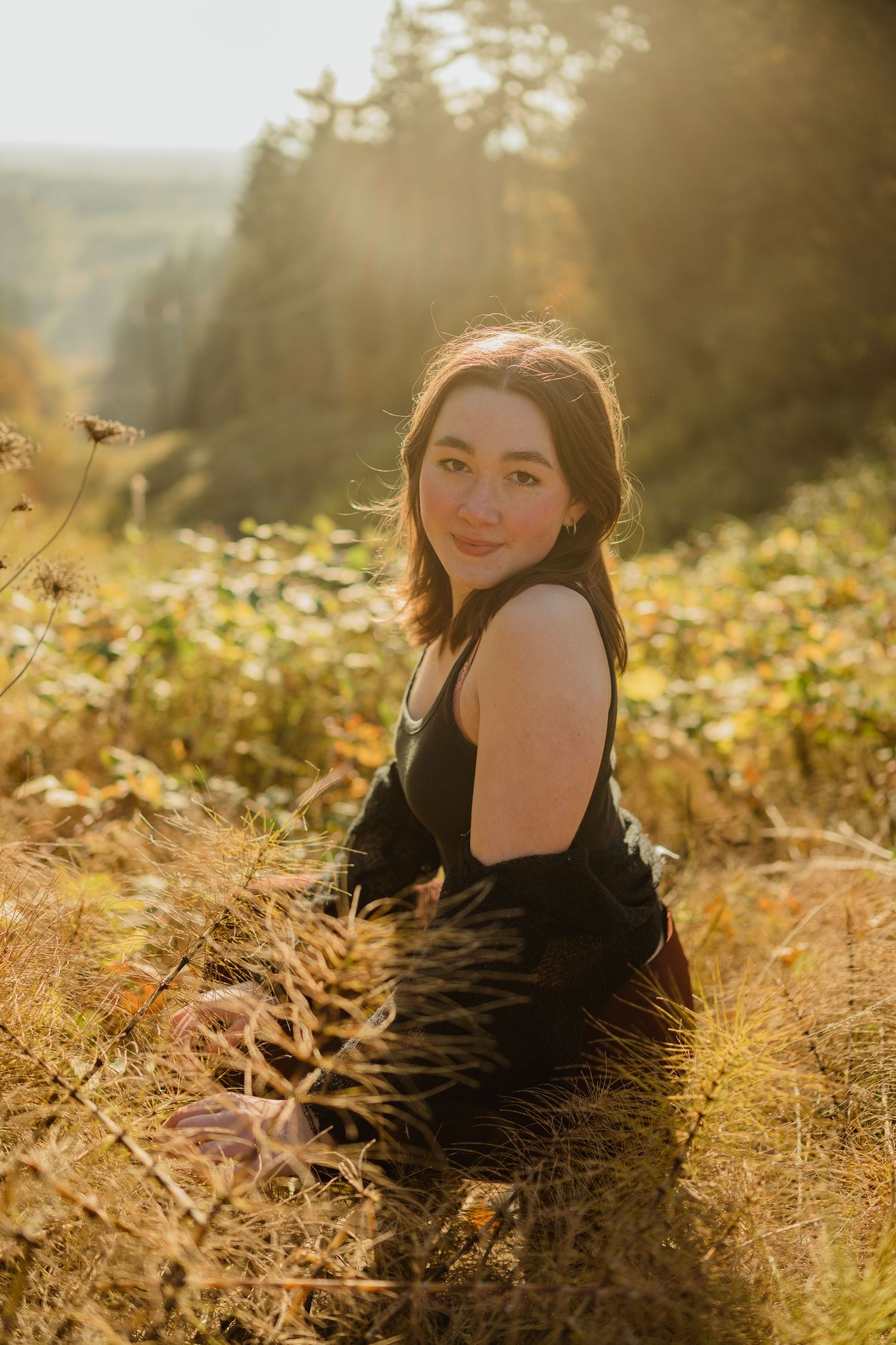 Dreamy golden hour portrait in field with sunlit autumn foliage.