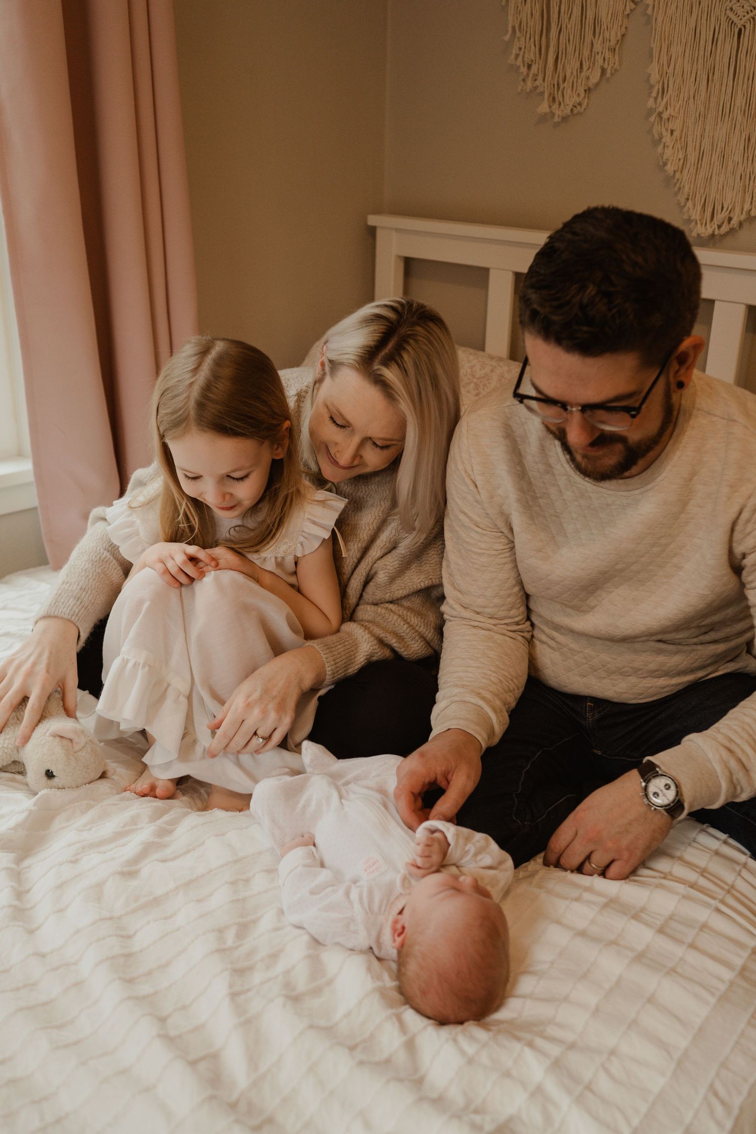 An intimate family moment on a bed with a newborn baby.