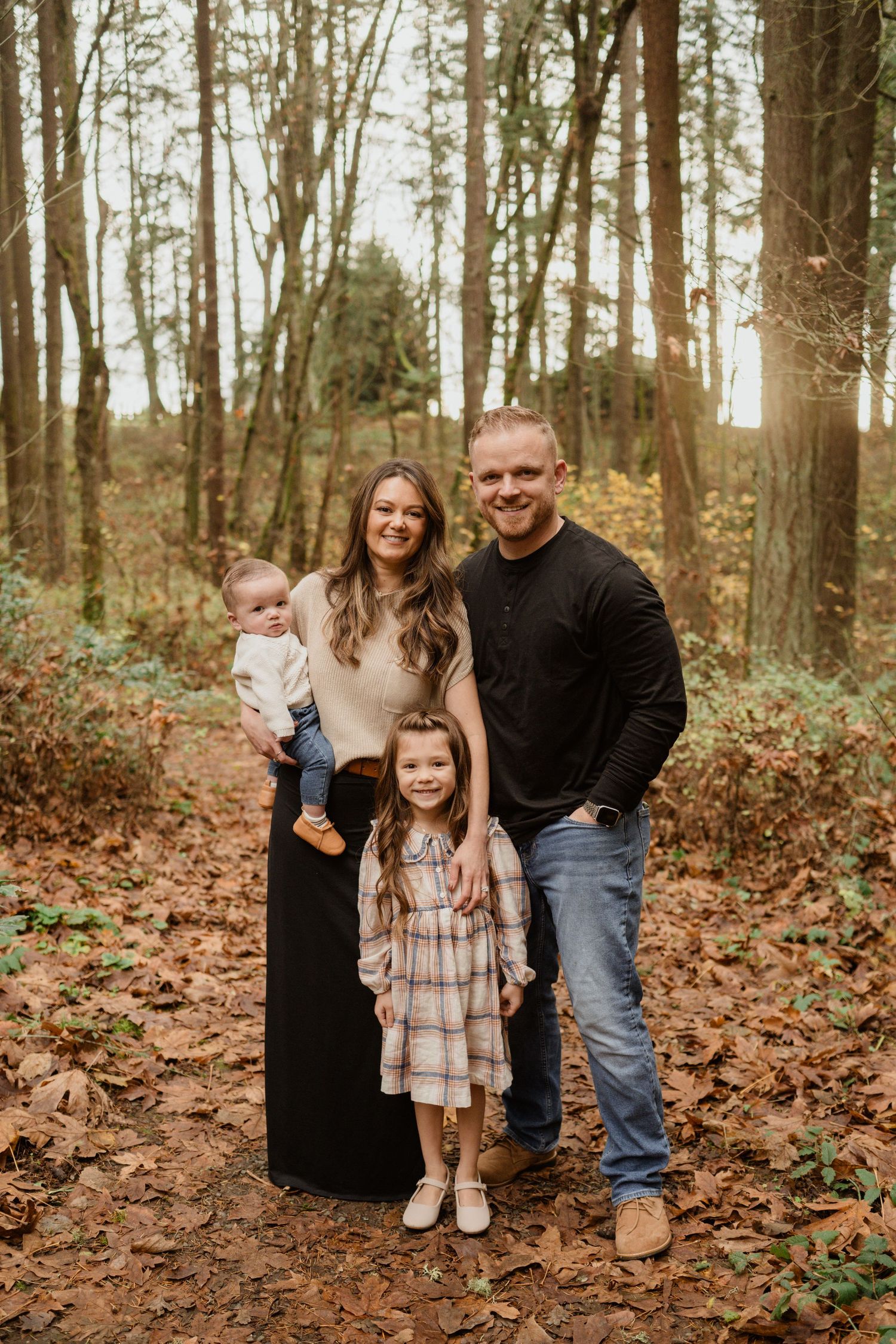 Heartwarming family portrait in an autumn forest with fallen leaves and natural lighting.