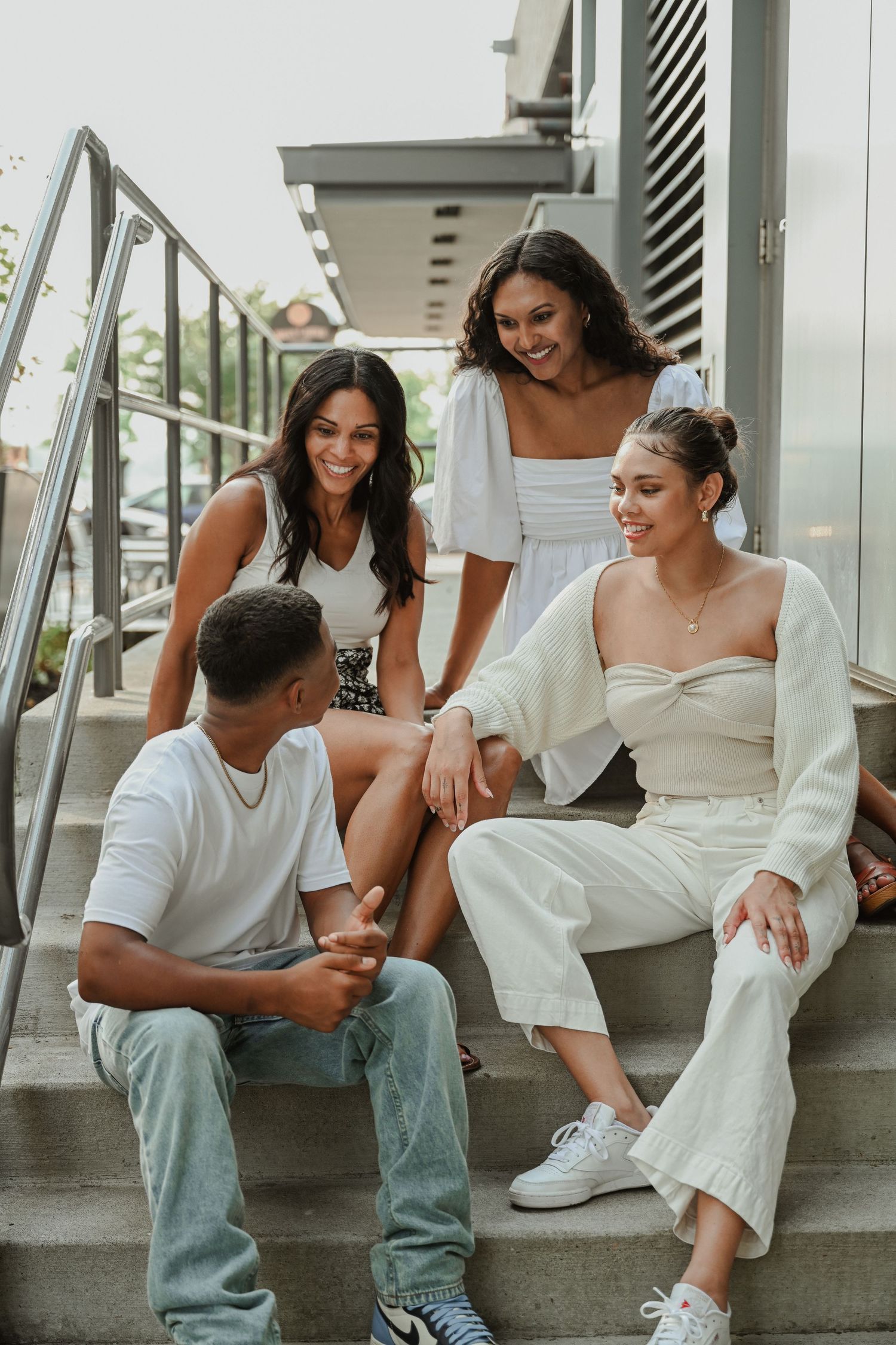Friends sharing laughs while sitting on outdoor staircase.