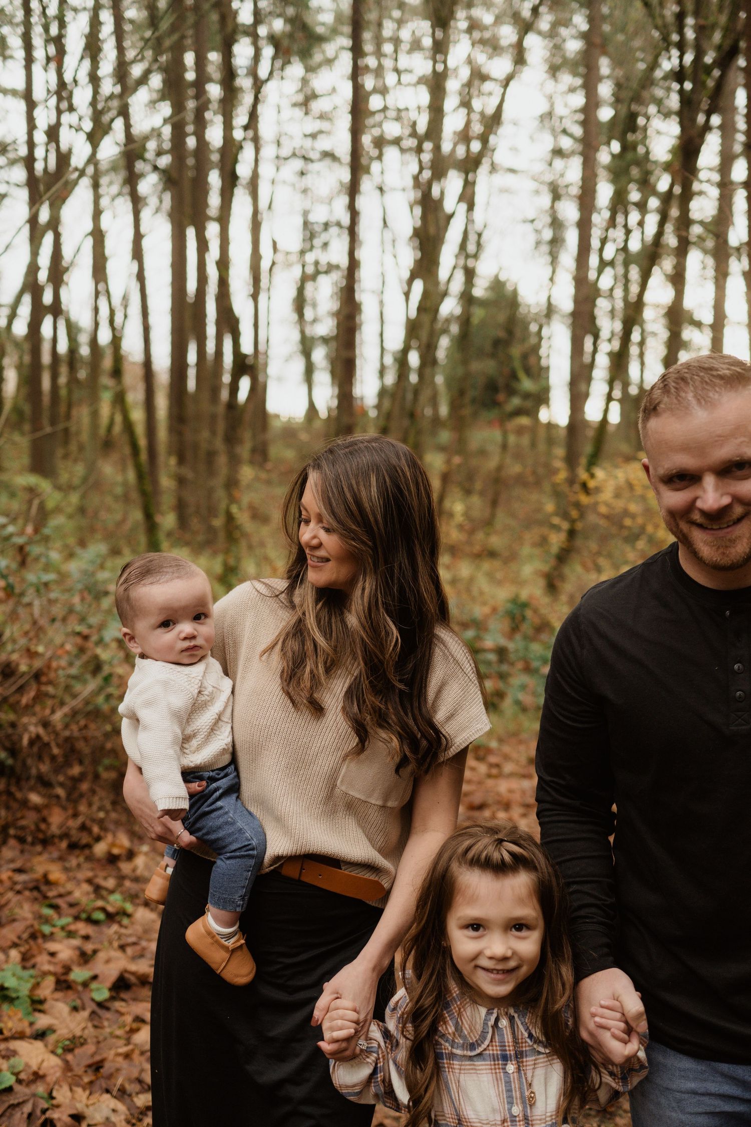 Candid family moment captured on a forest trail surrounded by fall foliage.