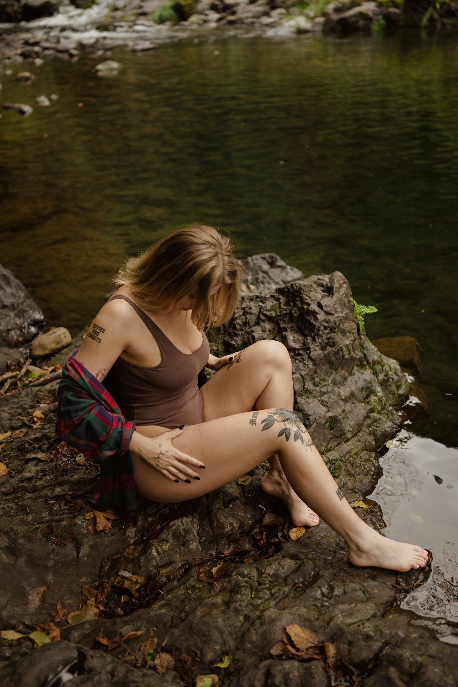 Peaceful moment sitting on rocks by forest stream.