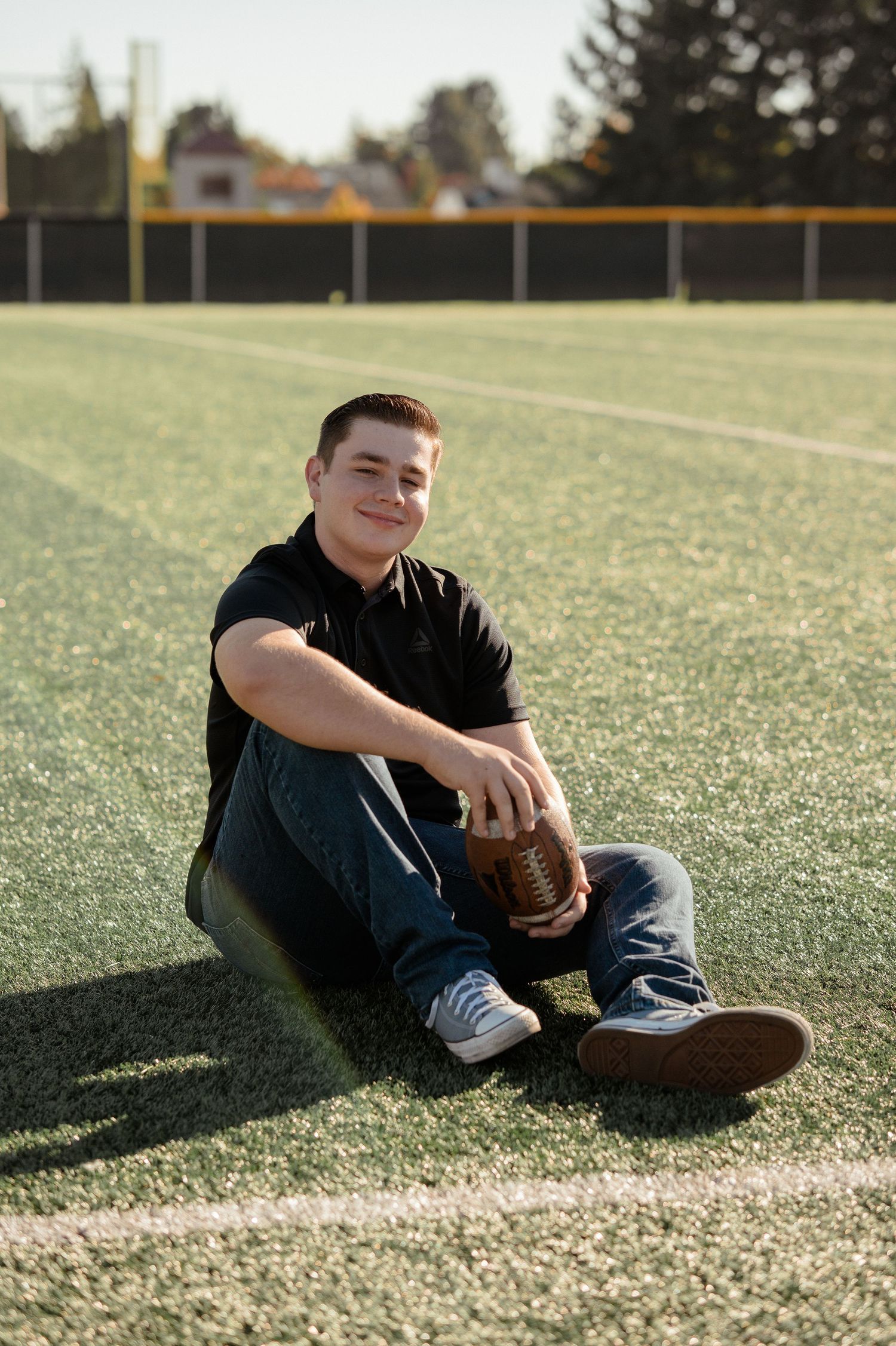 Person relaxing on sports field with baseball glove in casual attire.