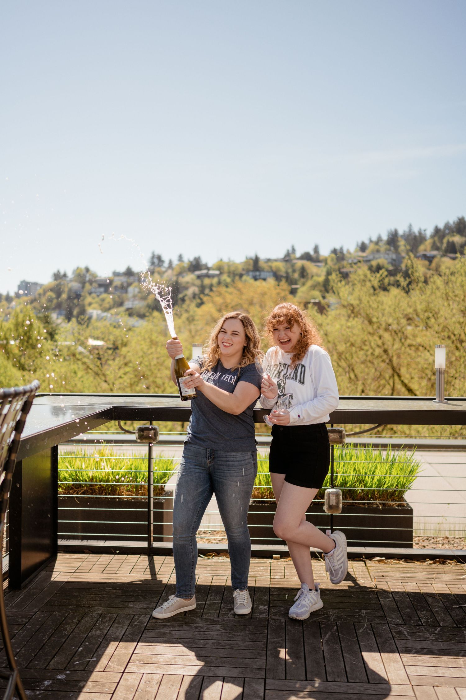 Friends in casual attire pose playfully on outdoor deck with hillside view.