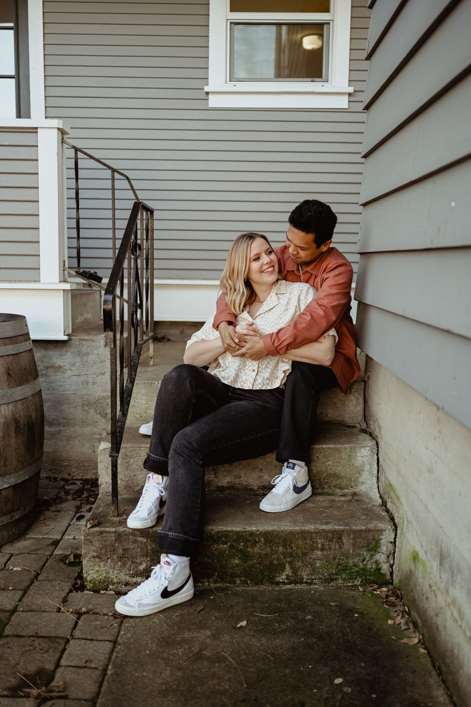A couple sharing a tender moment on concrete steps outside their home.
