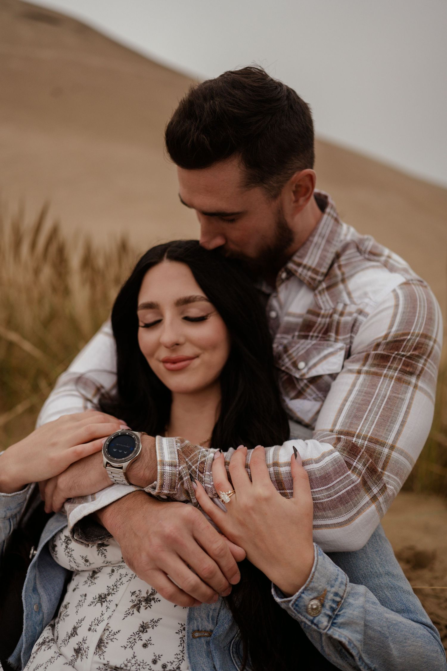 A tender embrace captured outdoors with soft natural lighting and gentle expressions.