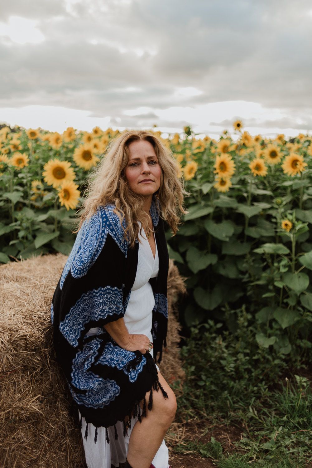 Bohemian fashion portrait with blue patterned kimono in sunflower field.