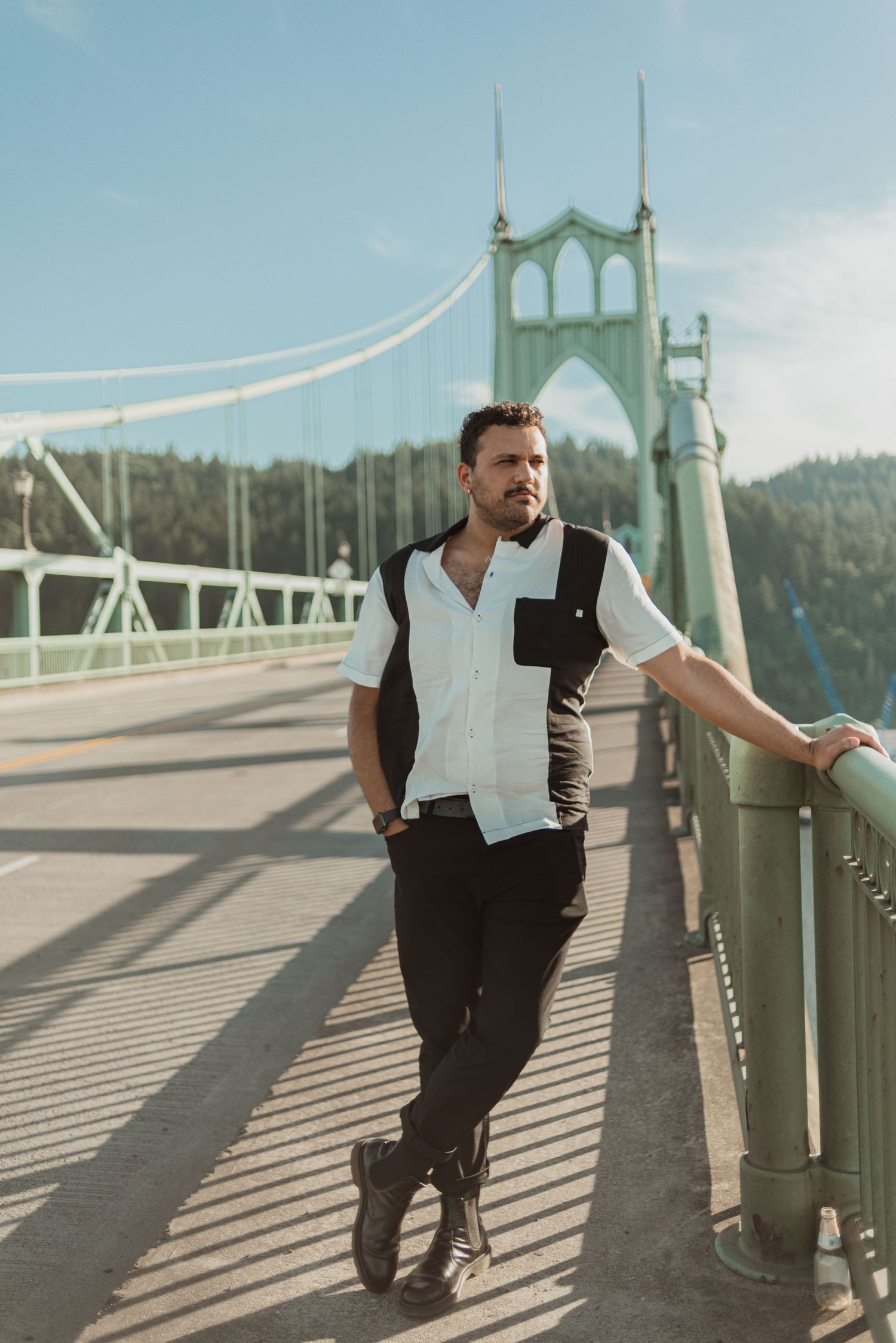 Person poses on iconic St. Johns Bridge in Portland against blue sky.