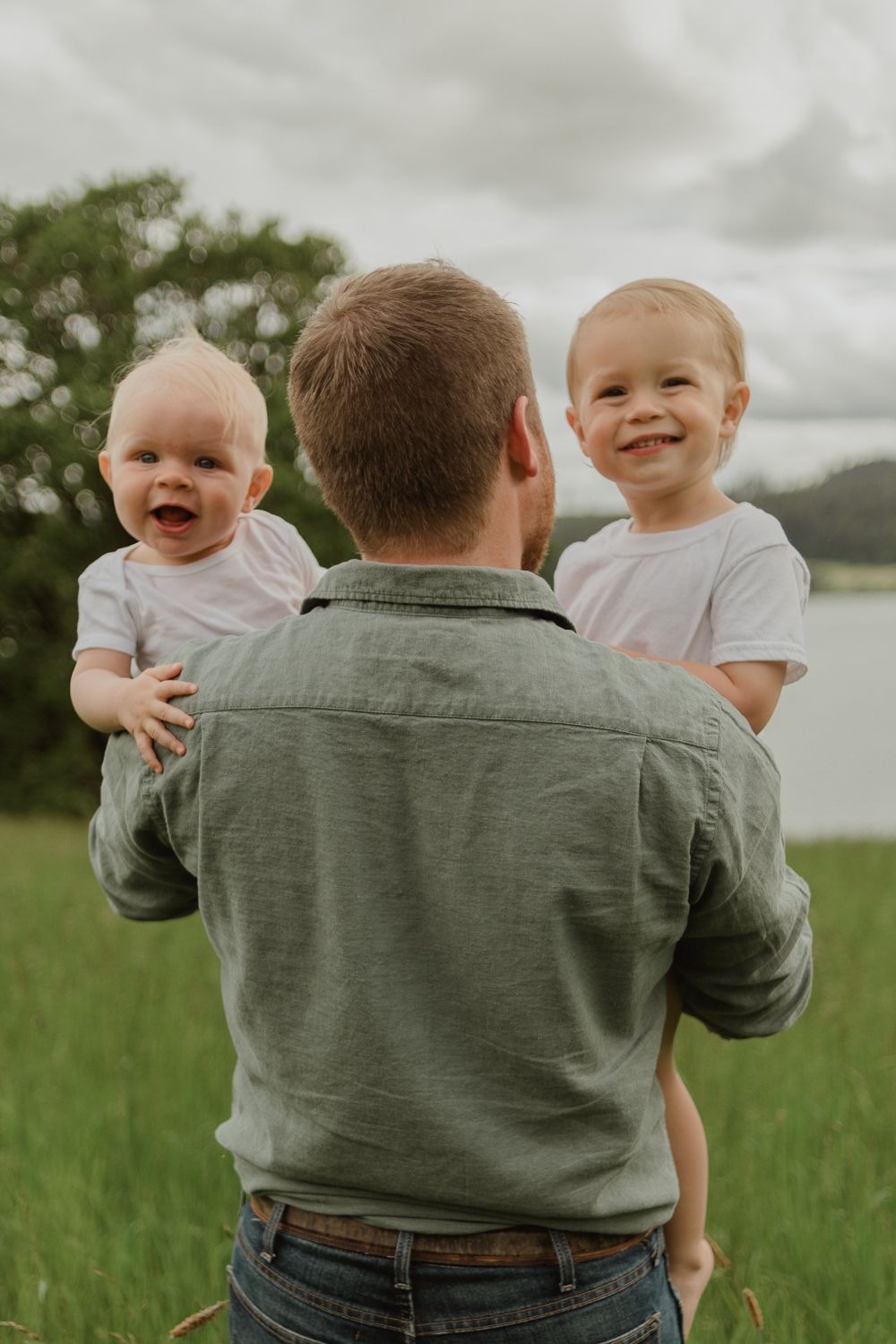 Joyful moment in grassy field with lake and cloudy sky in background.