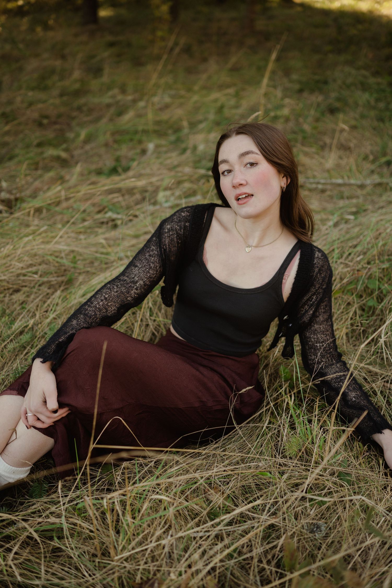 Fashion portrait in tall grass featuring black lace top and burgundy skirt.