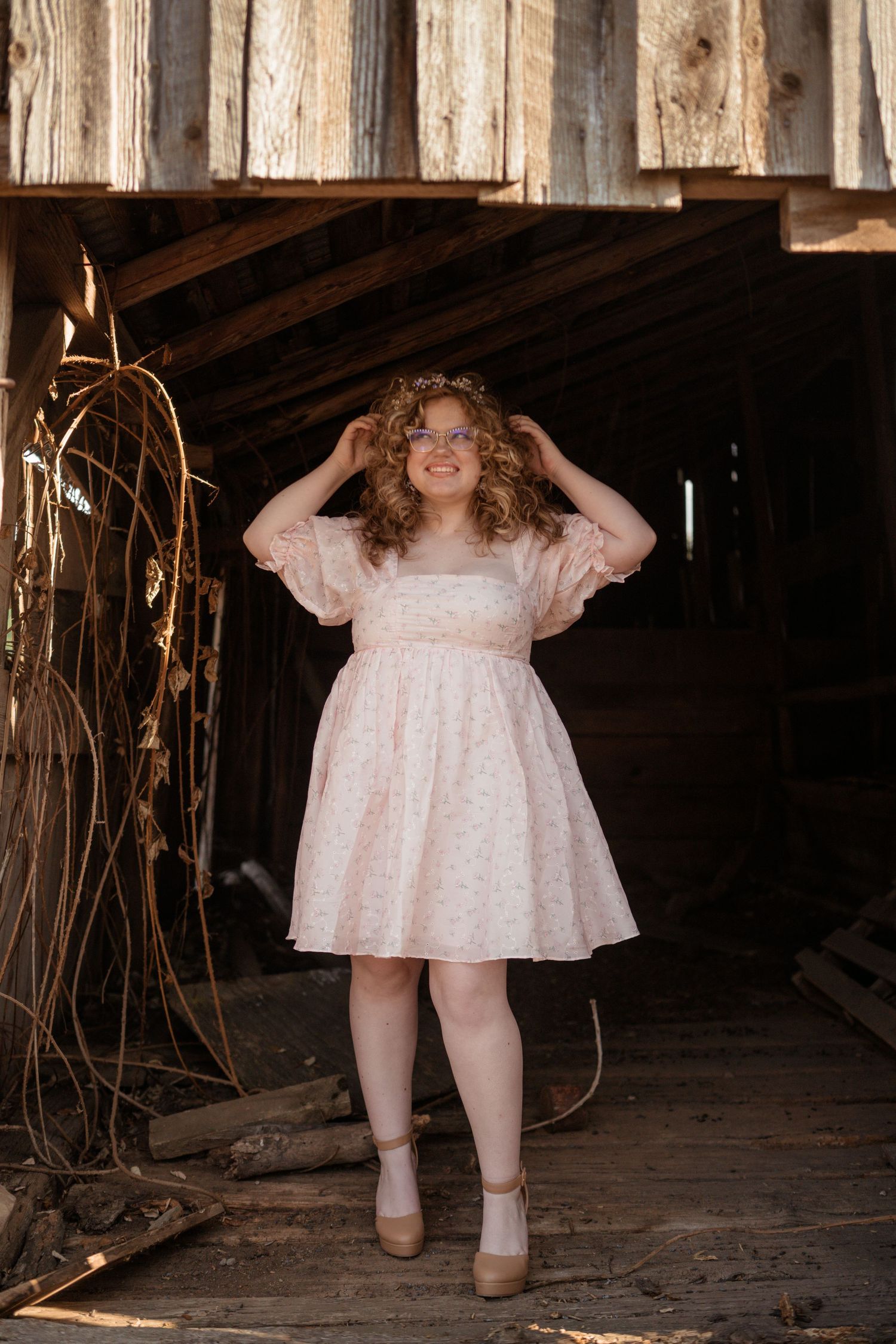 Feminine portrait in rustic barn wearing vintage-inspired pink dress.