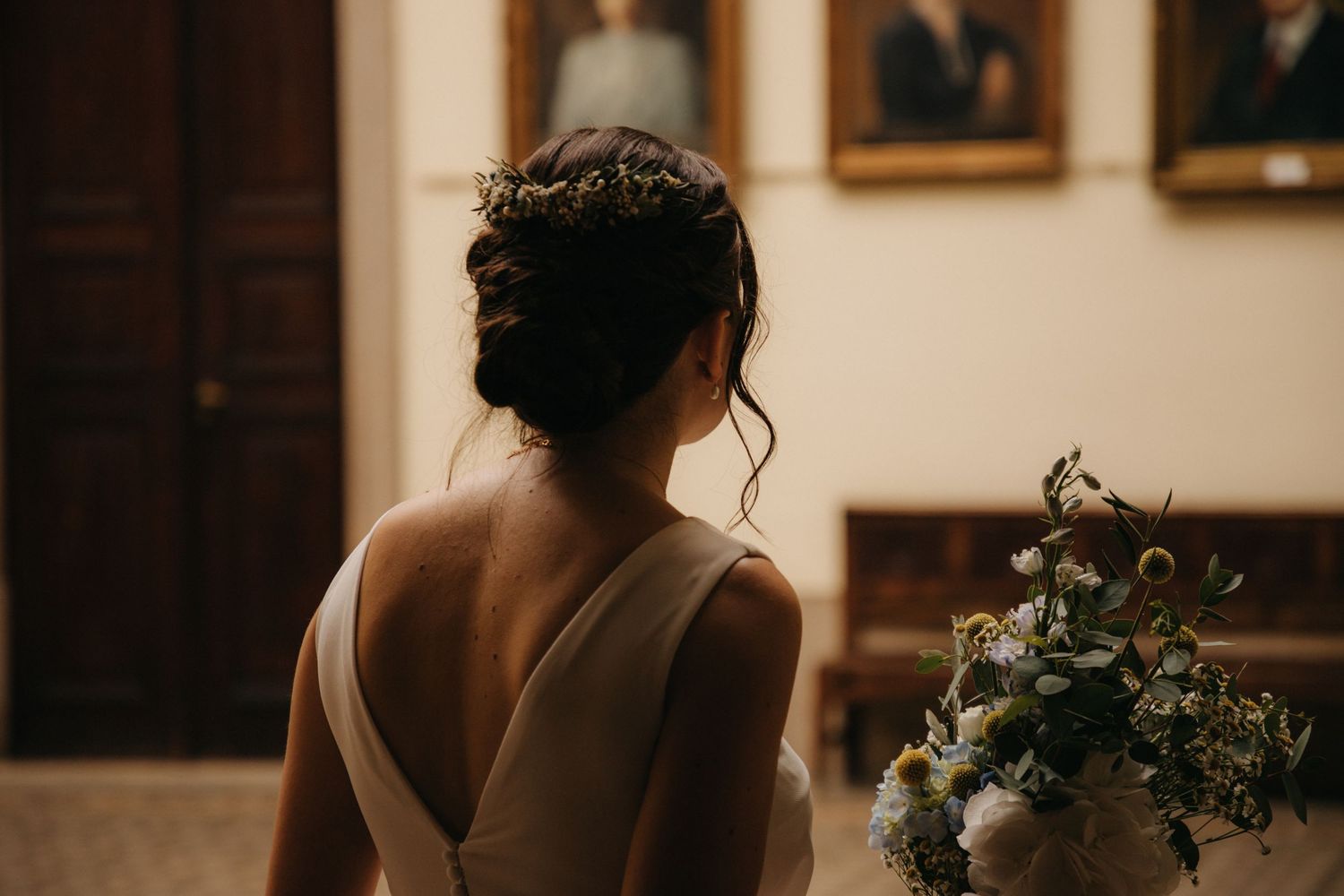Back view of wedding dress showing elegant V-cut design in formal indoor setting.